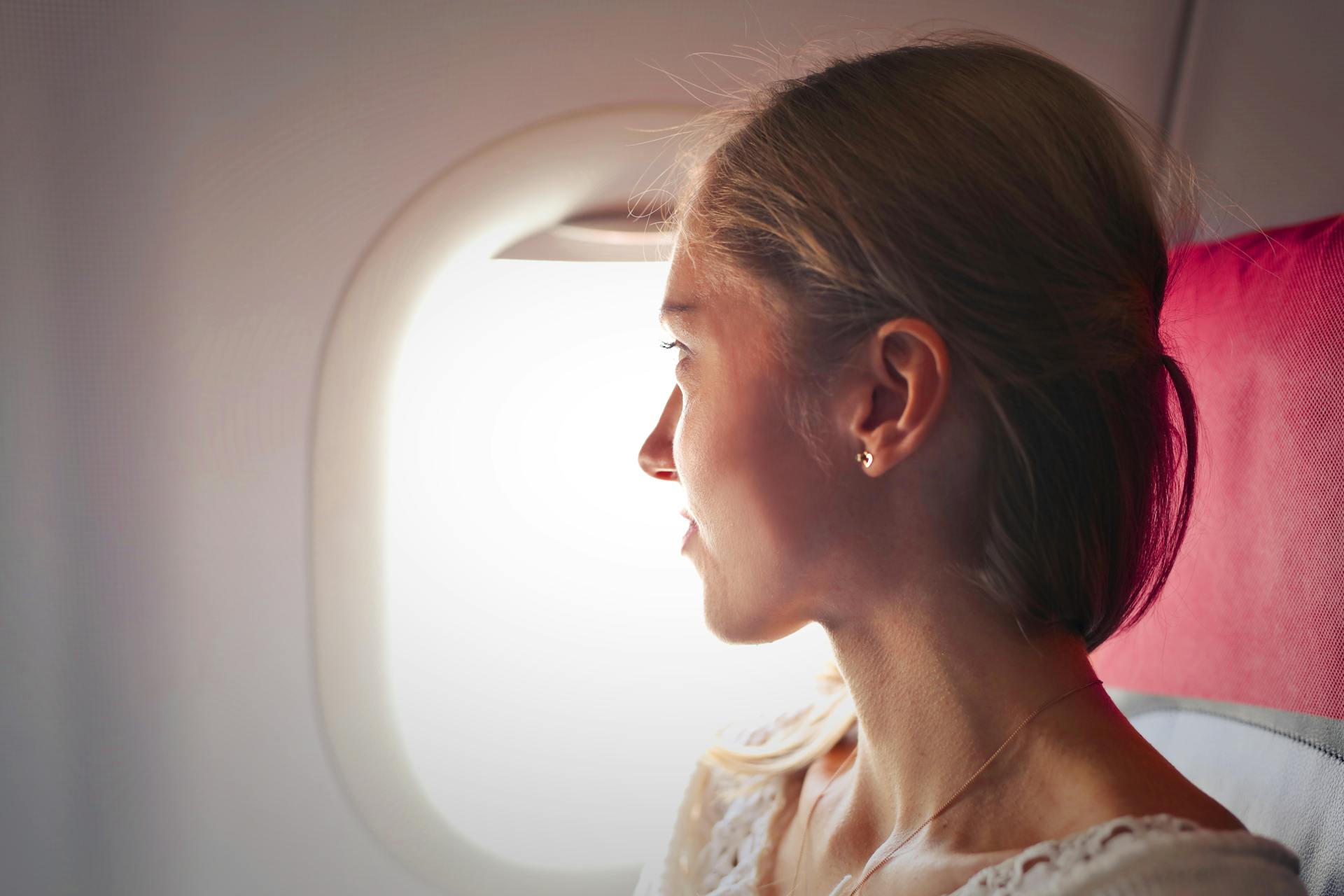 Una mujer mirando por la ventanilla de un avión | Fuente: Pexels