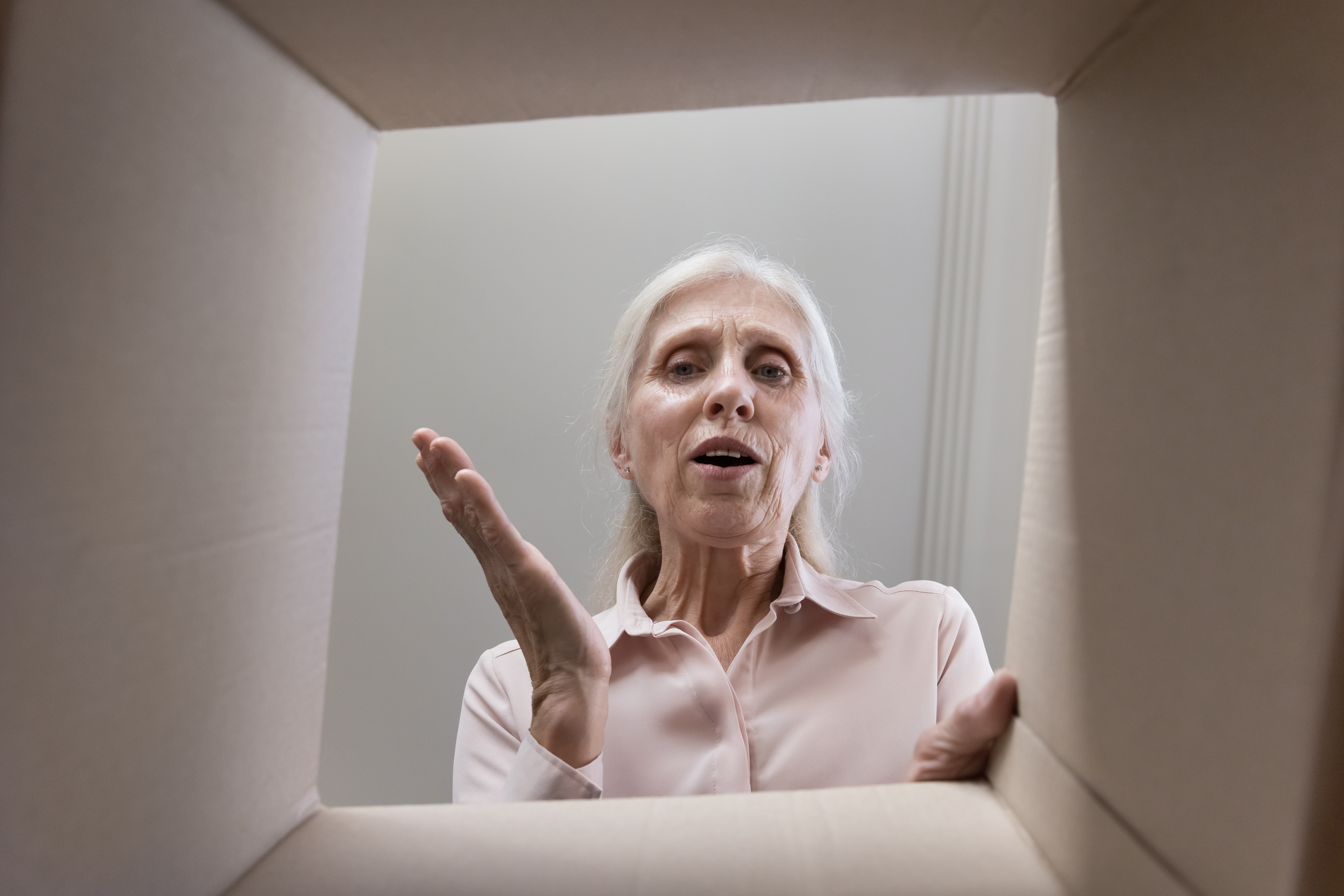 Mujer mayor mirando dentro de una caja de cartón | Foto: Shutterstock