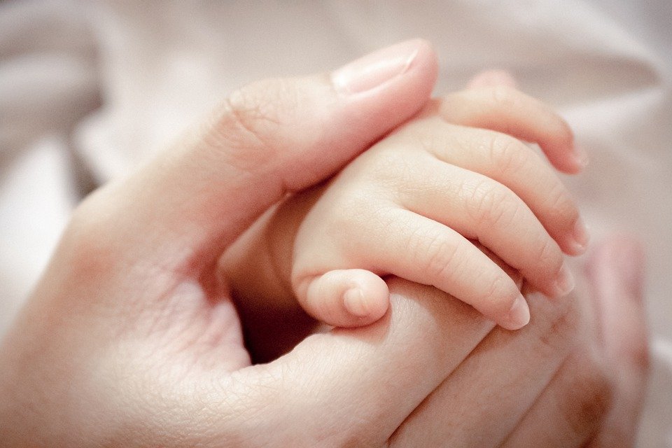 Mujer tomando la mano de un bebé. | Foto: Pixabay