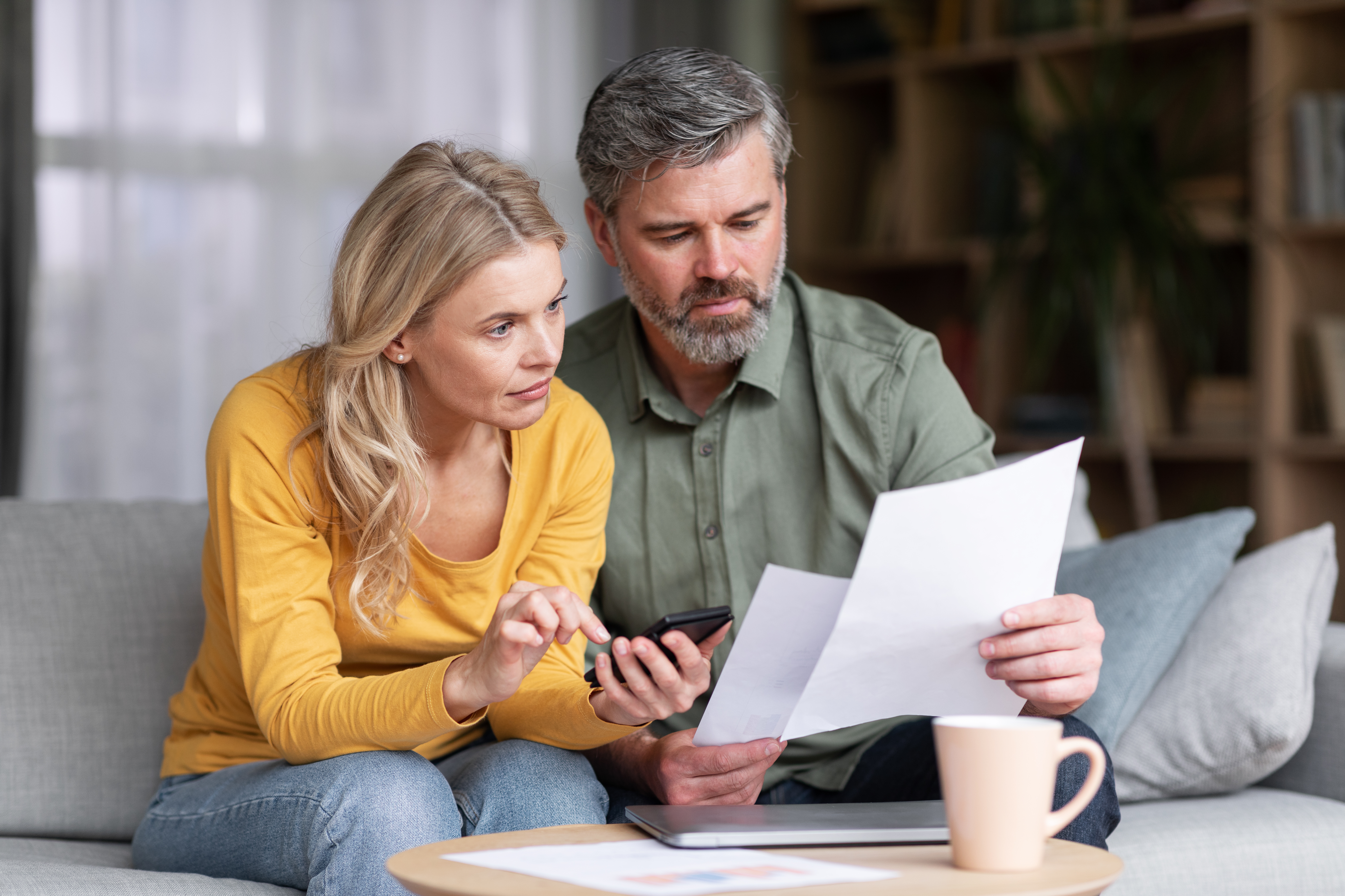 Pareja casada de mediana edad planificando juntos su presupuesto, leyendo papeles y calculando gastos | Fuente: Getty Images