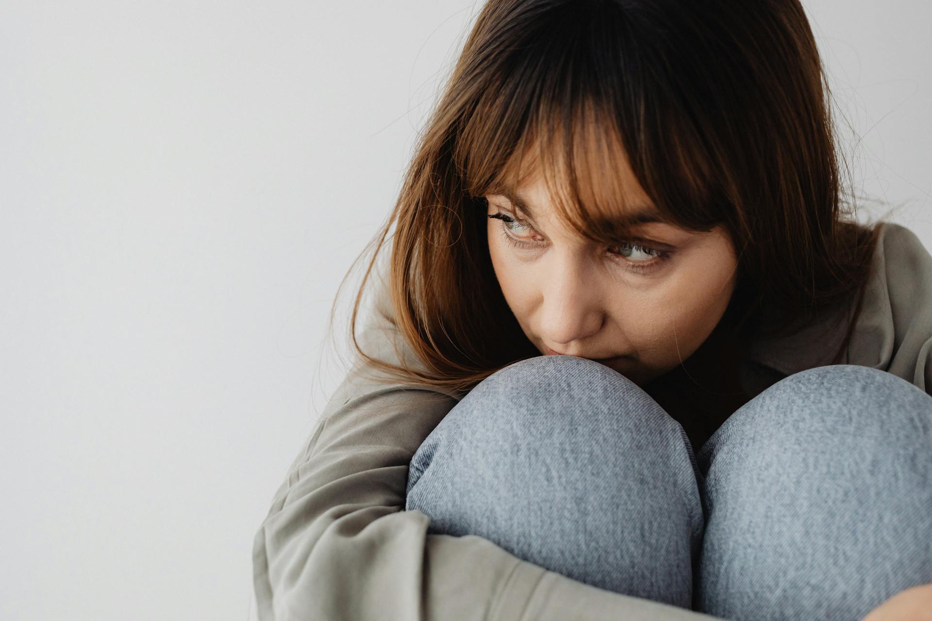 Una mujer angustiada acurrucada en la silla y mirando a su lado | Fuente: Pexels