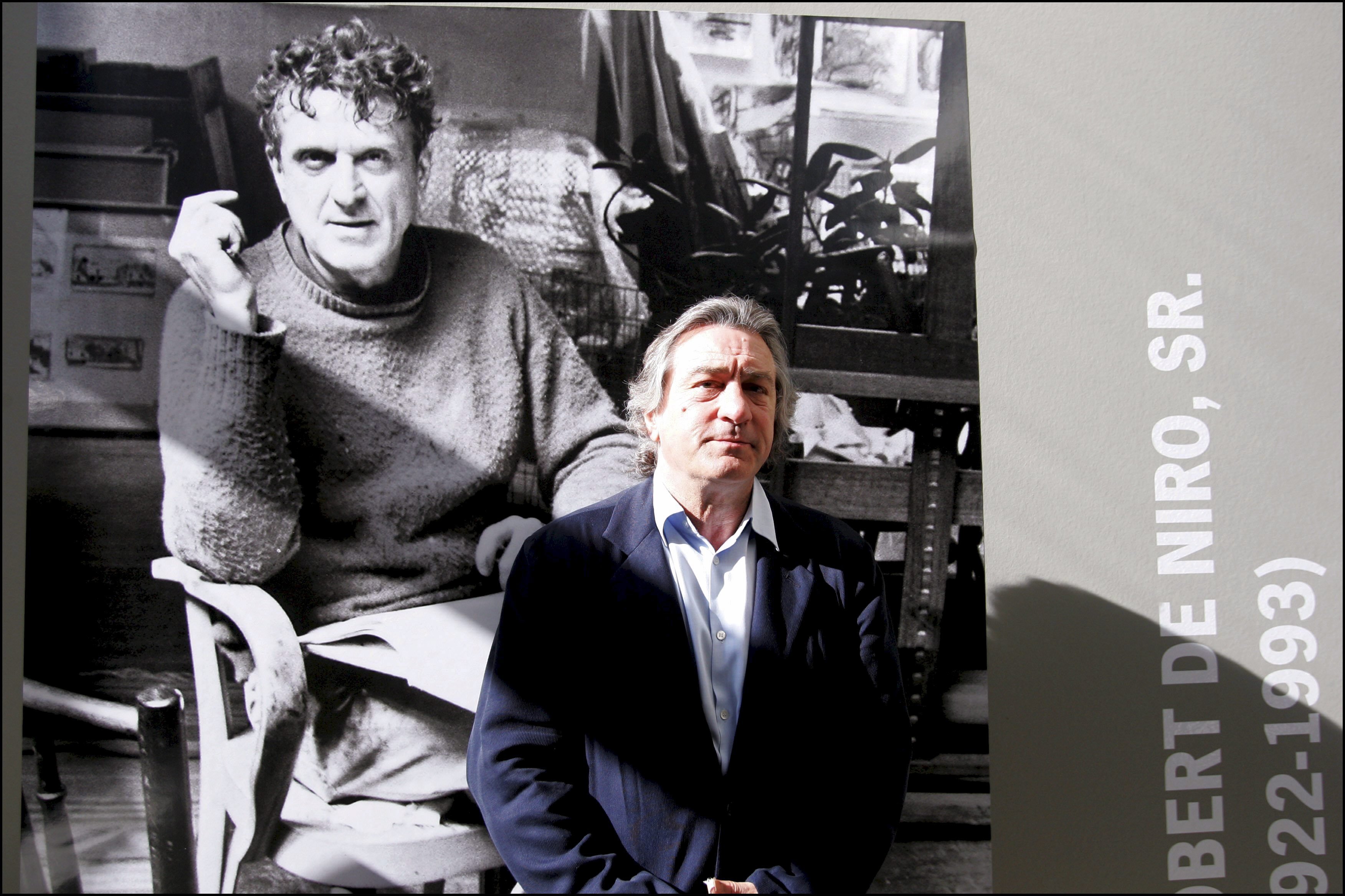 Robert De Niro posa junto a un retrato de su padre Robert Sr. en una exposición de pinturas de Robert De Niro Sr. en La Piscine en Roubaix, Francia el 18 de junio de 2005 | Foto: Getty Images