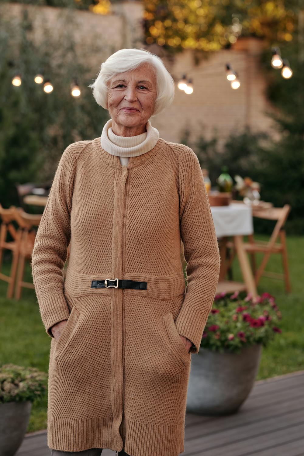 Una mujer sonriente en su porche ⏐ Fuente: Pexels