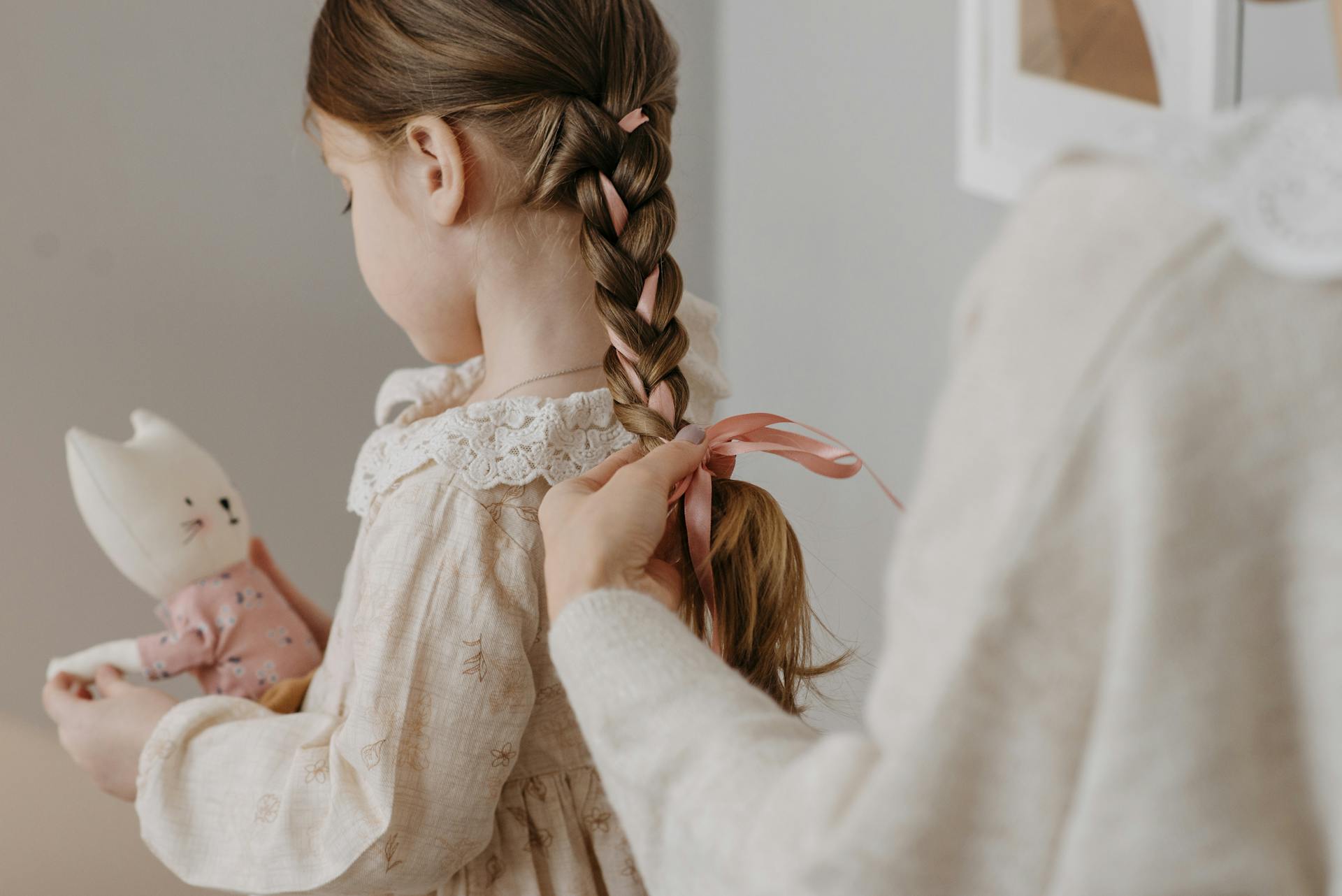 Uma mulher amarrando uma fita no cabelo da filha | Fonte: Pexels