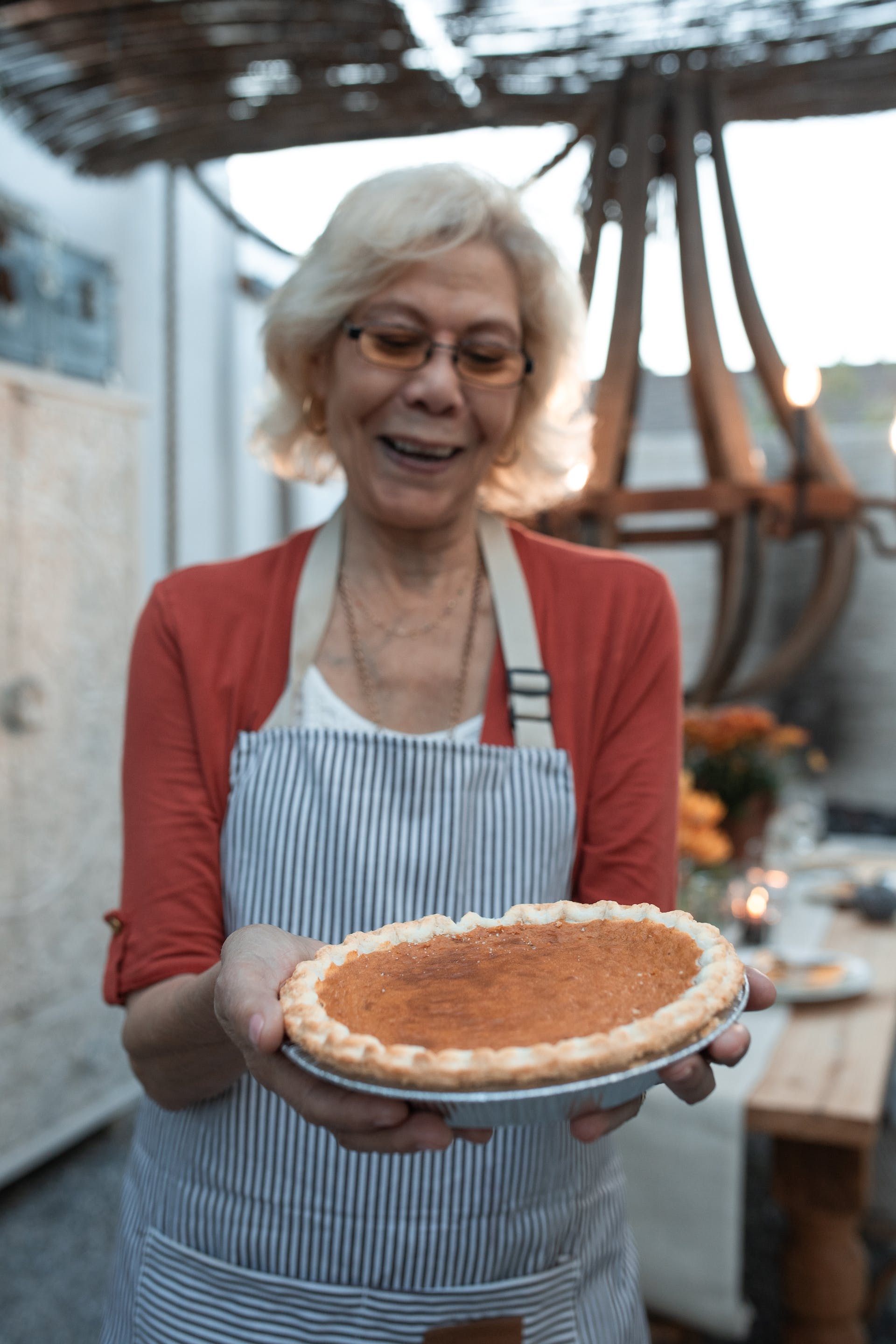 Anciana sonriente con una tarta de calabaza en la mano | Foto: Pexels