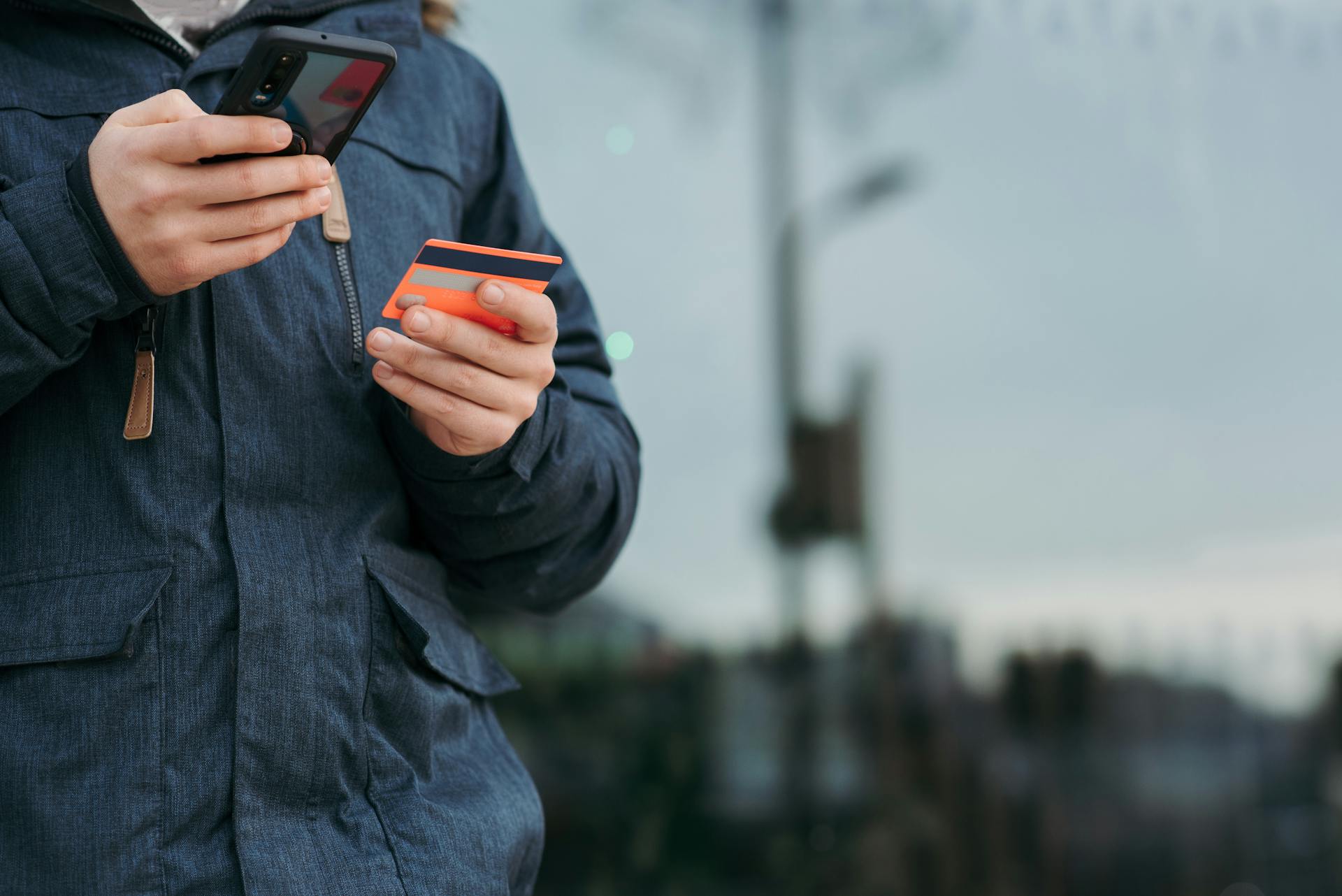 Un hombre con su tarjeta y su teléfono | Fuente: Pexels