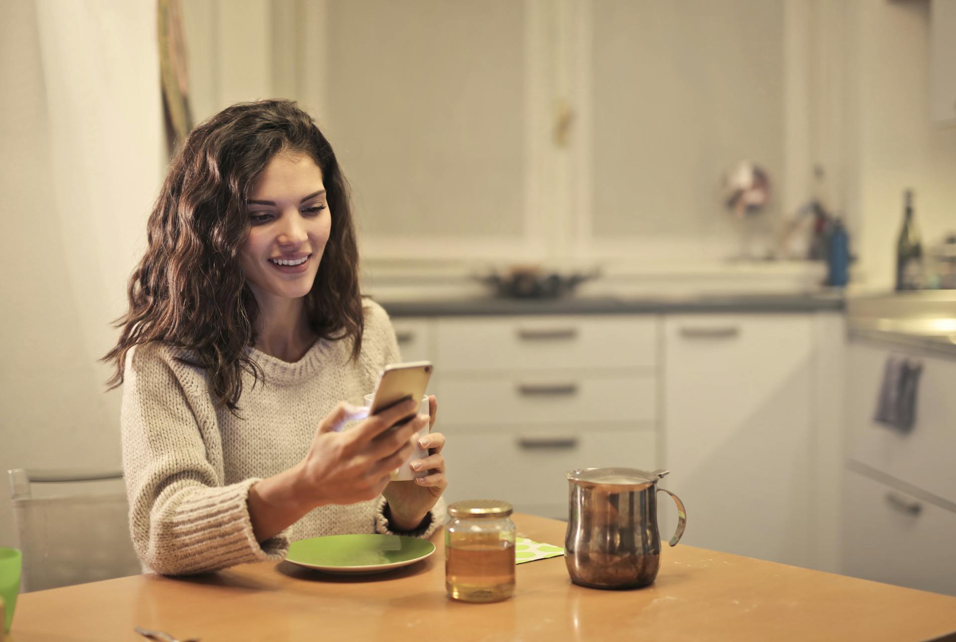 Una mujer bebiendo té y usando su smartphone | Fuente: Pexels