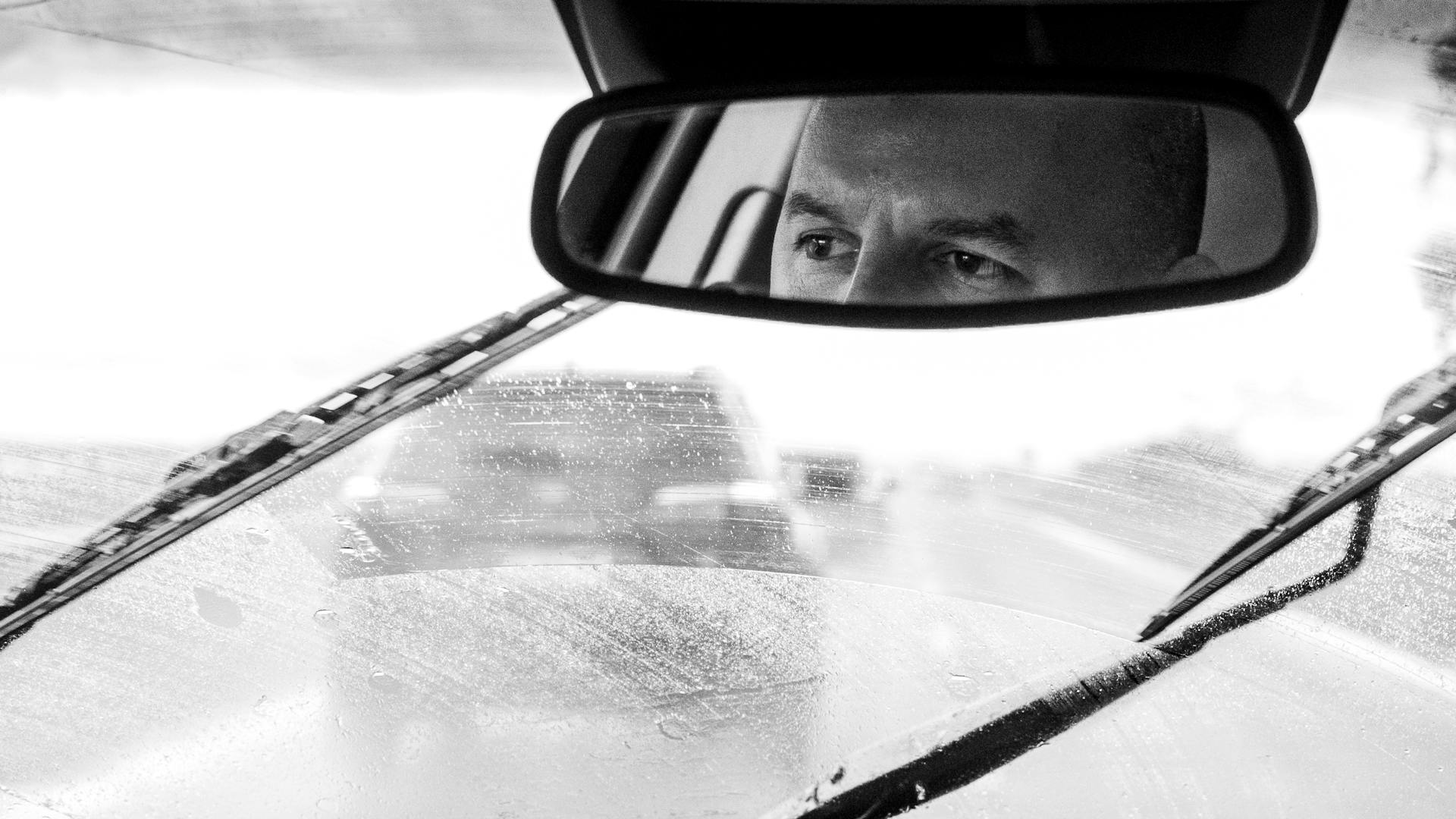 Reflejo de los ojos de un hombre en el espejo retrovisor | Fuente: Pexels