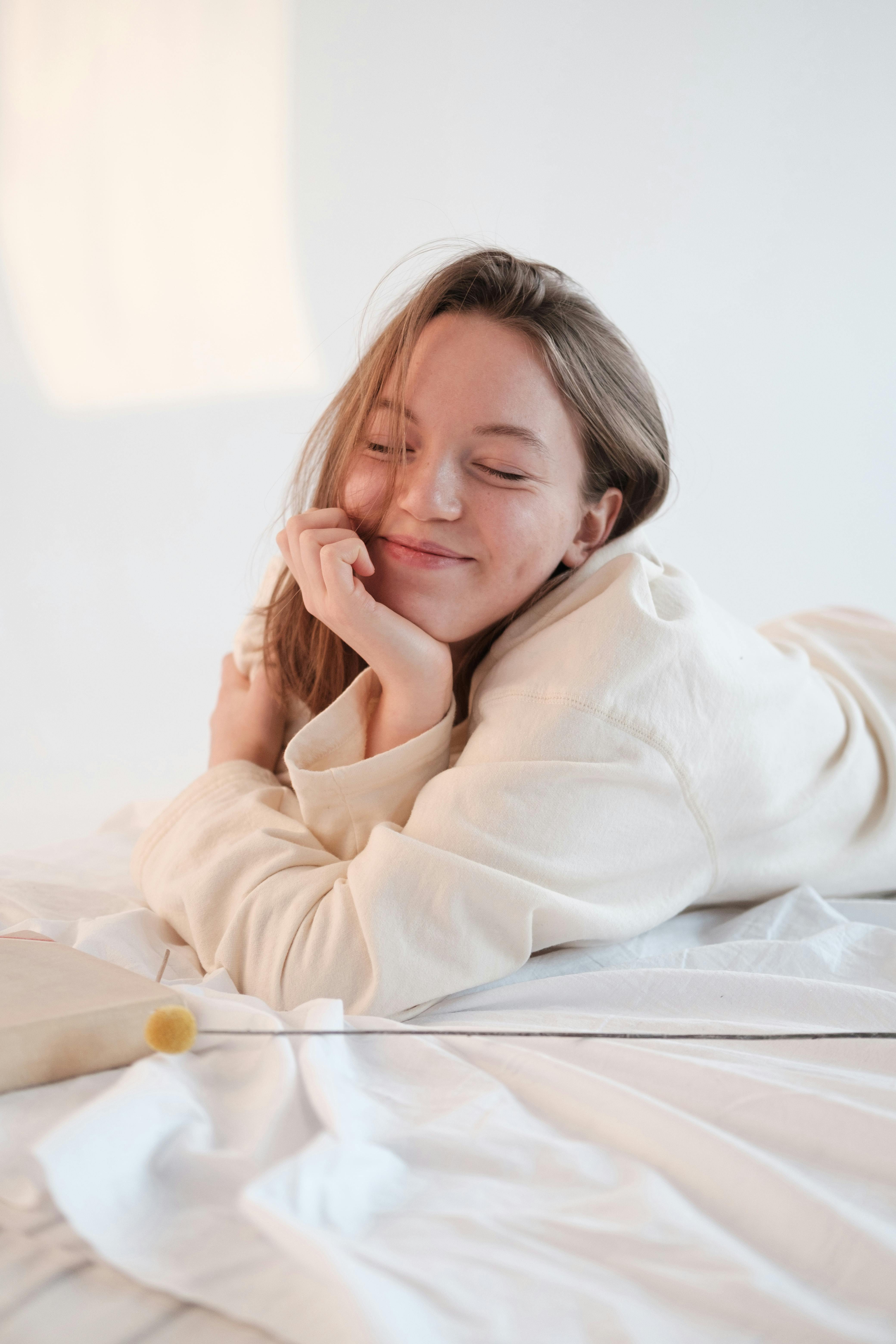 Una mujer feliz tumbada en una cama | Fuente: Pexels