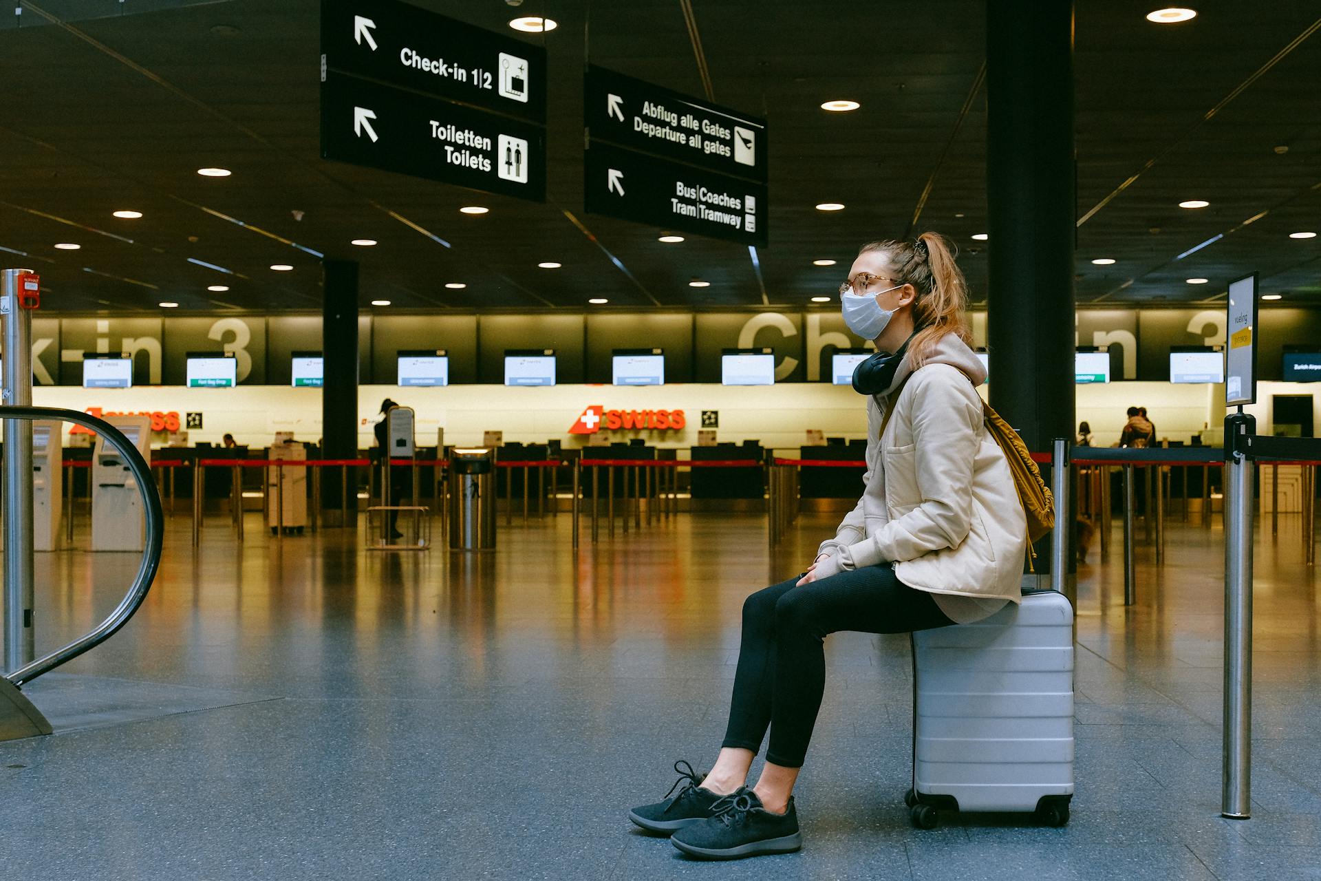 Mujer sentada sobre una maleta en un aeropuerto | Foto: Pexels