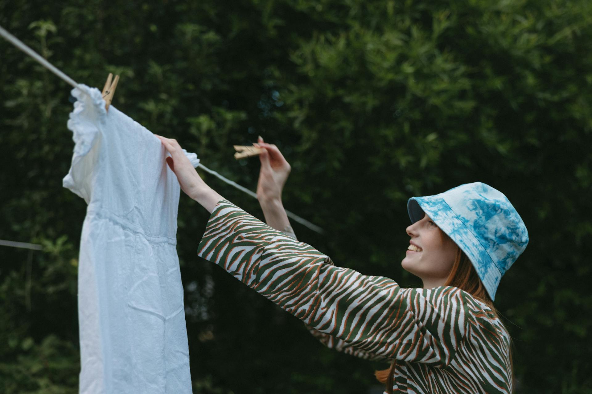 Una mujer sonriente colgando un vestido en un tendedero | Fuente: Pexels