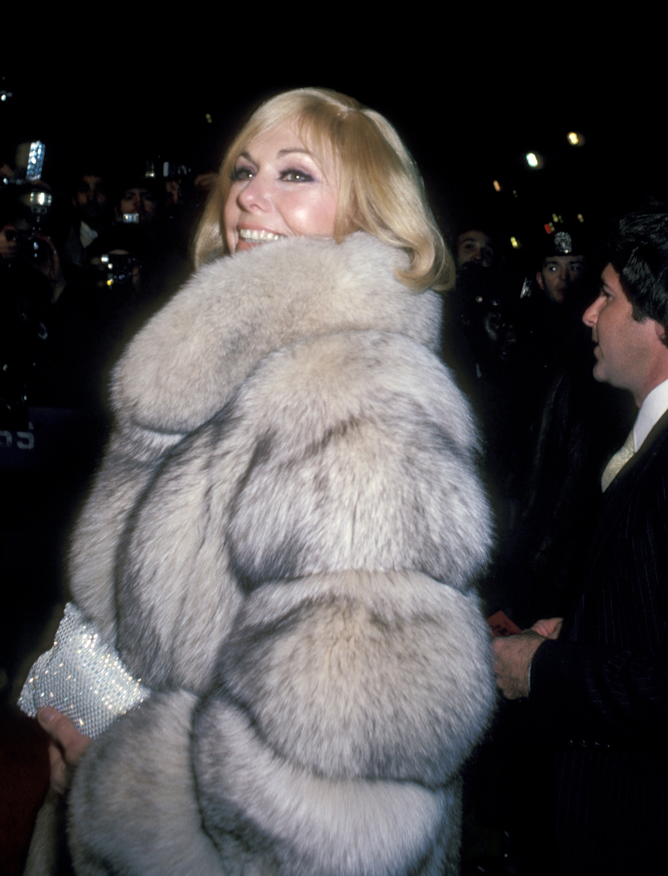 Kim Novak llega a un evento relacionado con el cine con un abrigo de piel muy voluminoso y llevando un bolso de mano brillante. | Fuente: Getty Images