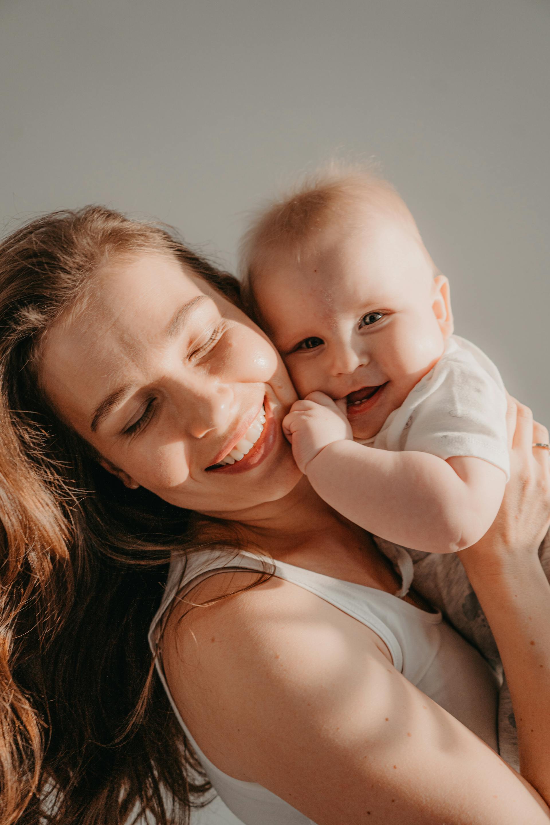 Una mujer feliz con un bebé sonriente en brazos | Fuente: Pexels