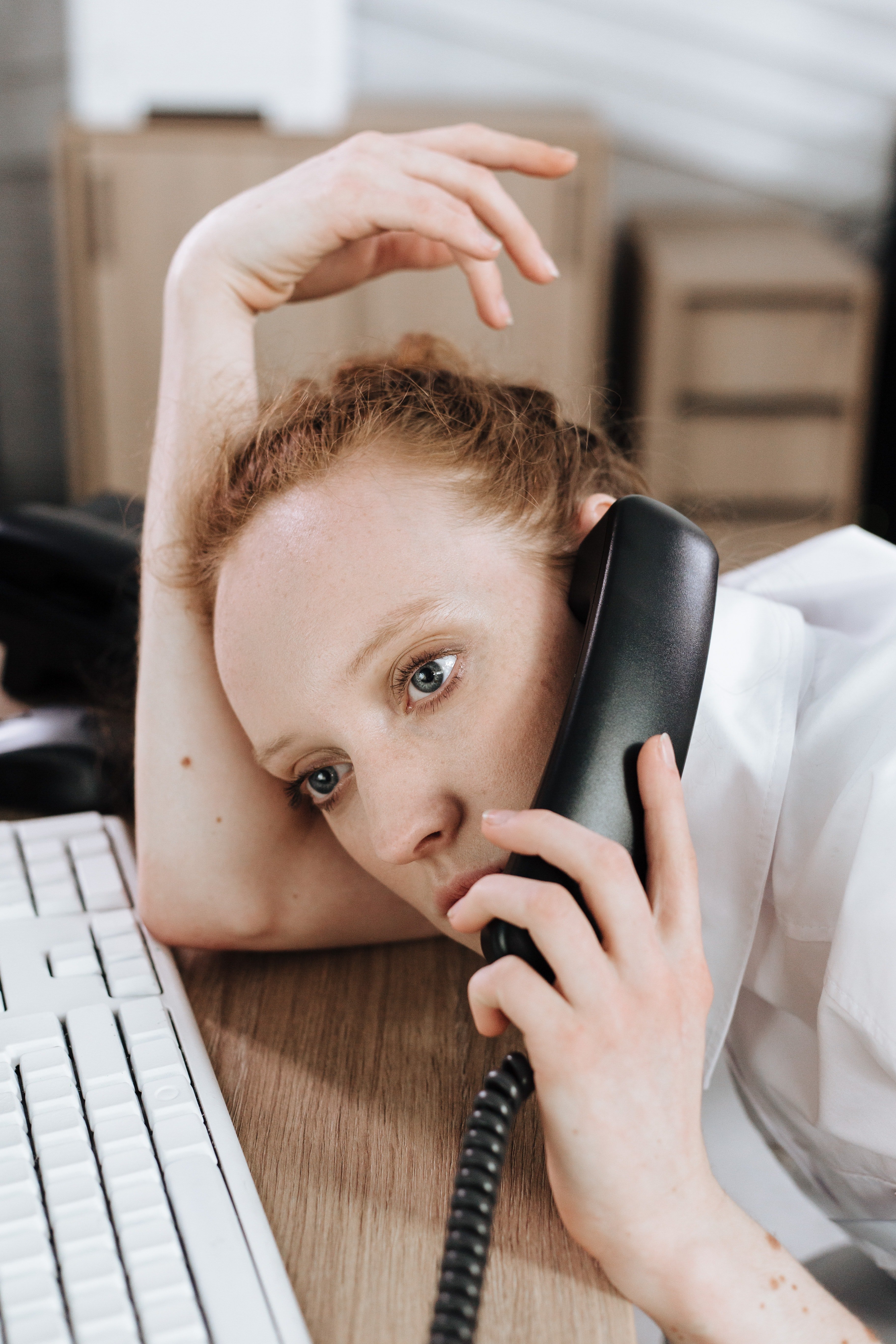 Una mujer hablando por teléfono recostada sobre un escritorio. | Foto: Pexels