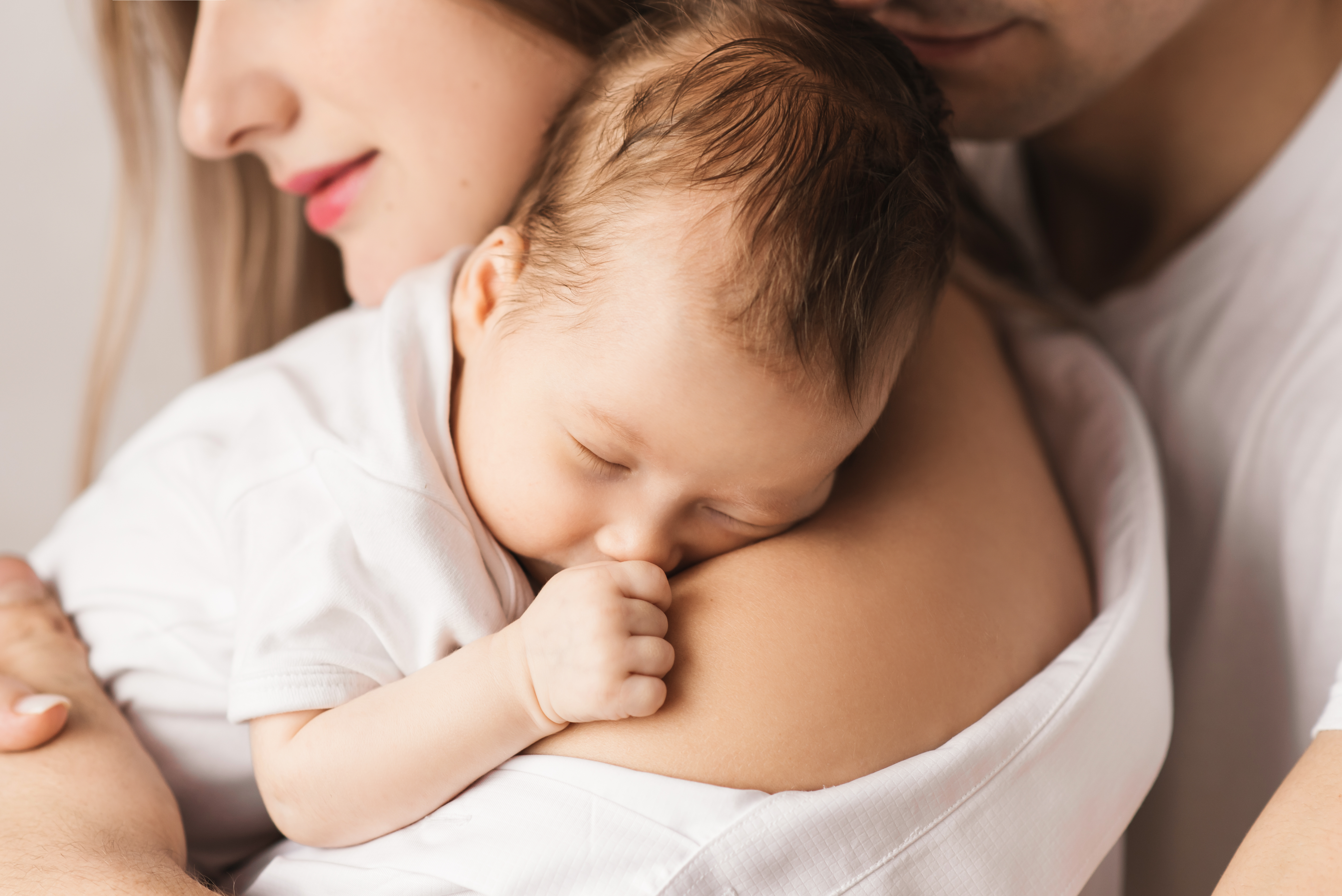 Una madre sostiene a su bebé recién nacido con su marido detrás | Foto: Shutterstock