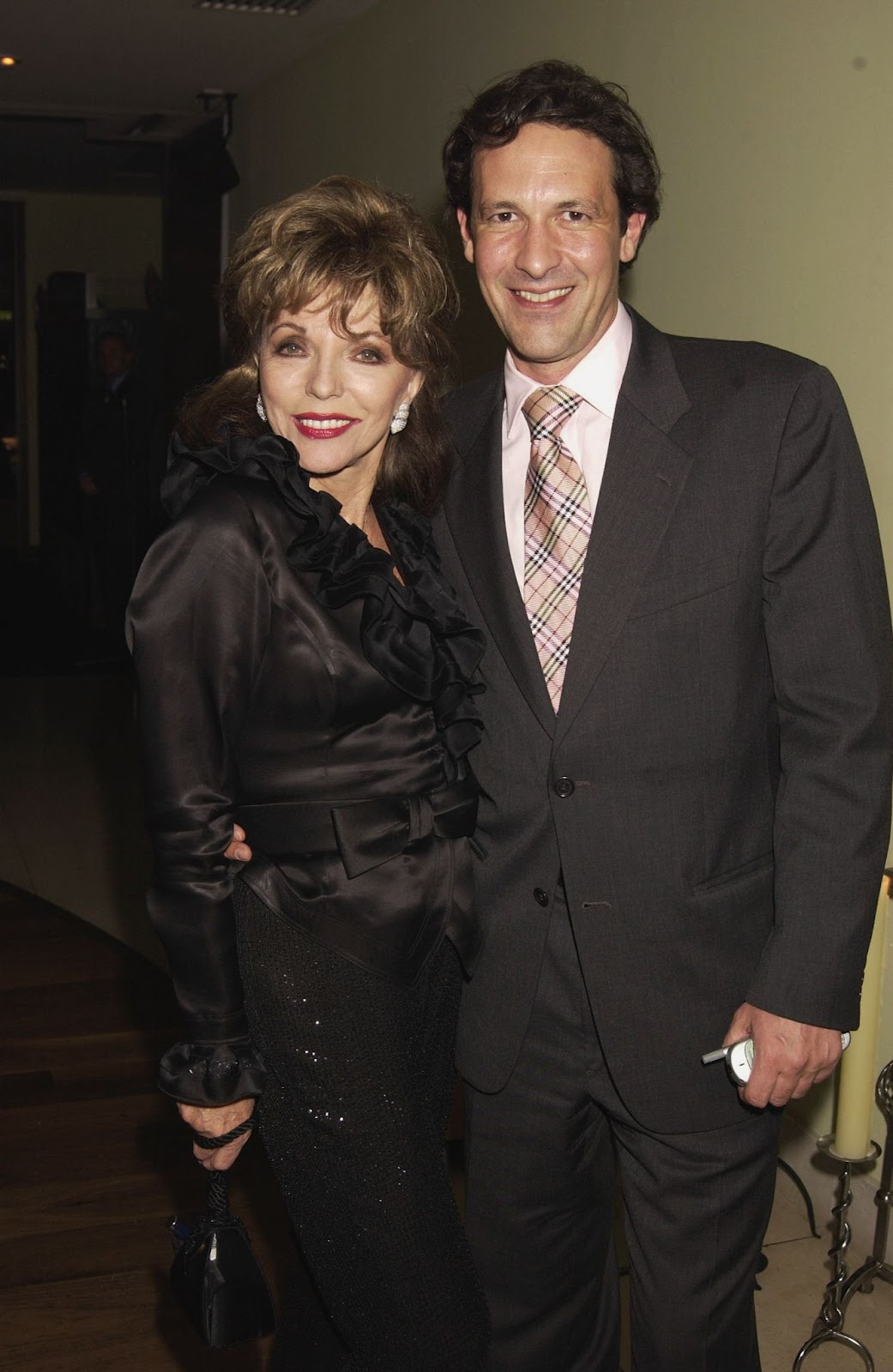 En 2002, Joan Collins y Percy Gibson fueron fotografiados juntos en una fiesta. Su floreciente relación siguió acaparando la atención, y la pareja mostró un fuerte vínculo desde el principio | Fuente: Getty Images