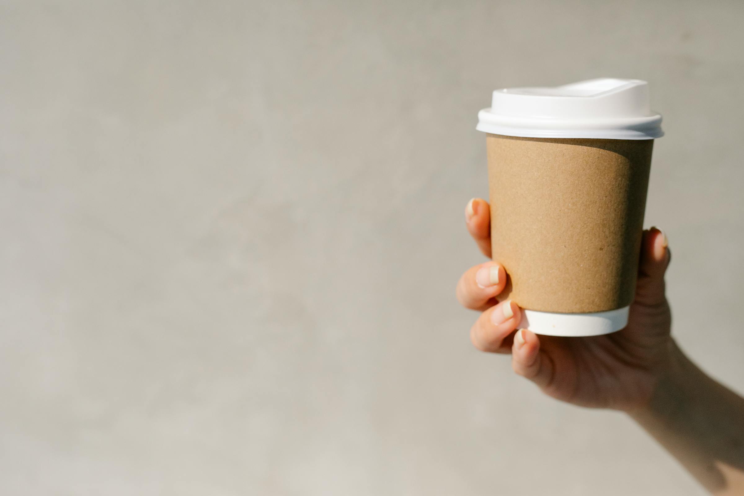 Una mano sujetando una taza de café para llevar | Fuente: Pexels