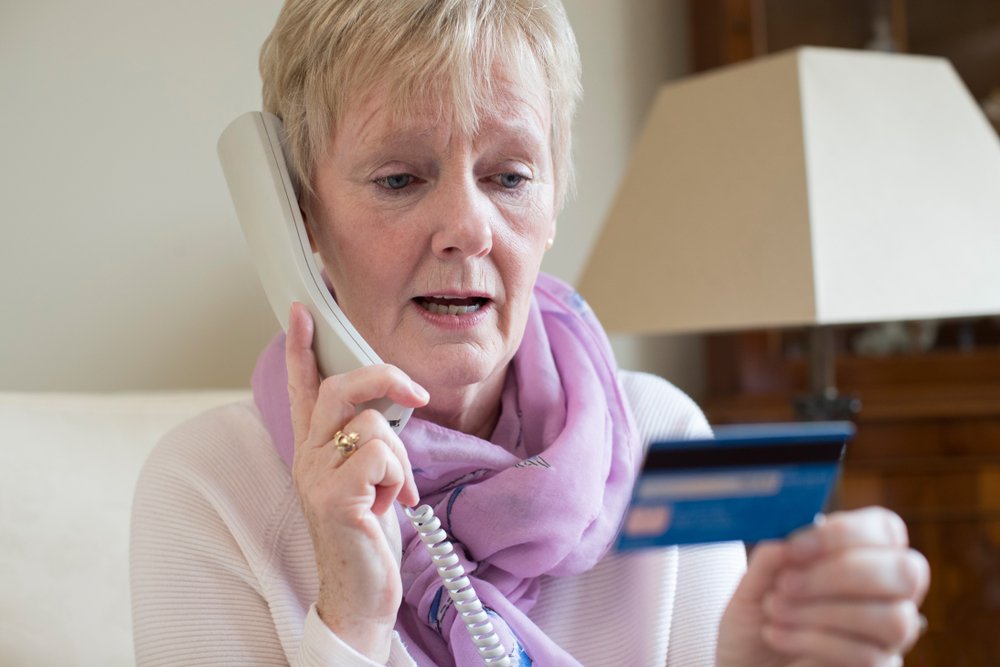 Mujer mayor dando datos de su tarjeta bancaria por teléfono. Fuente: Shutterstock