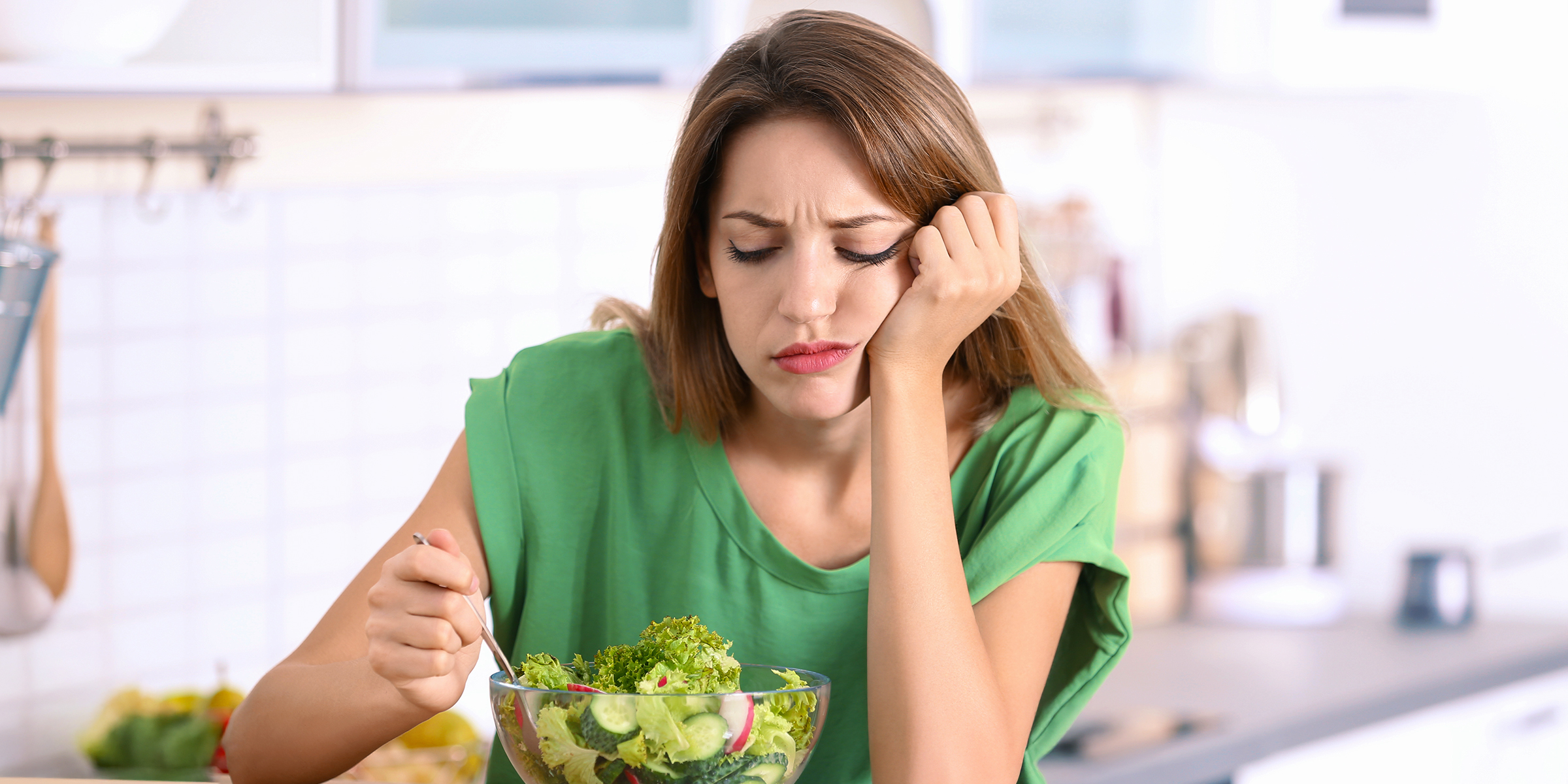 Una mujer aburrida mirando su ensalada | Fuente: Shutterstock