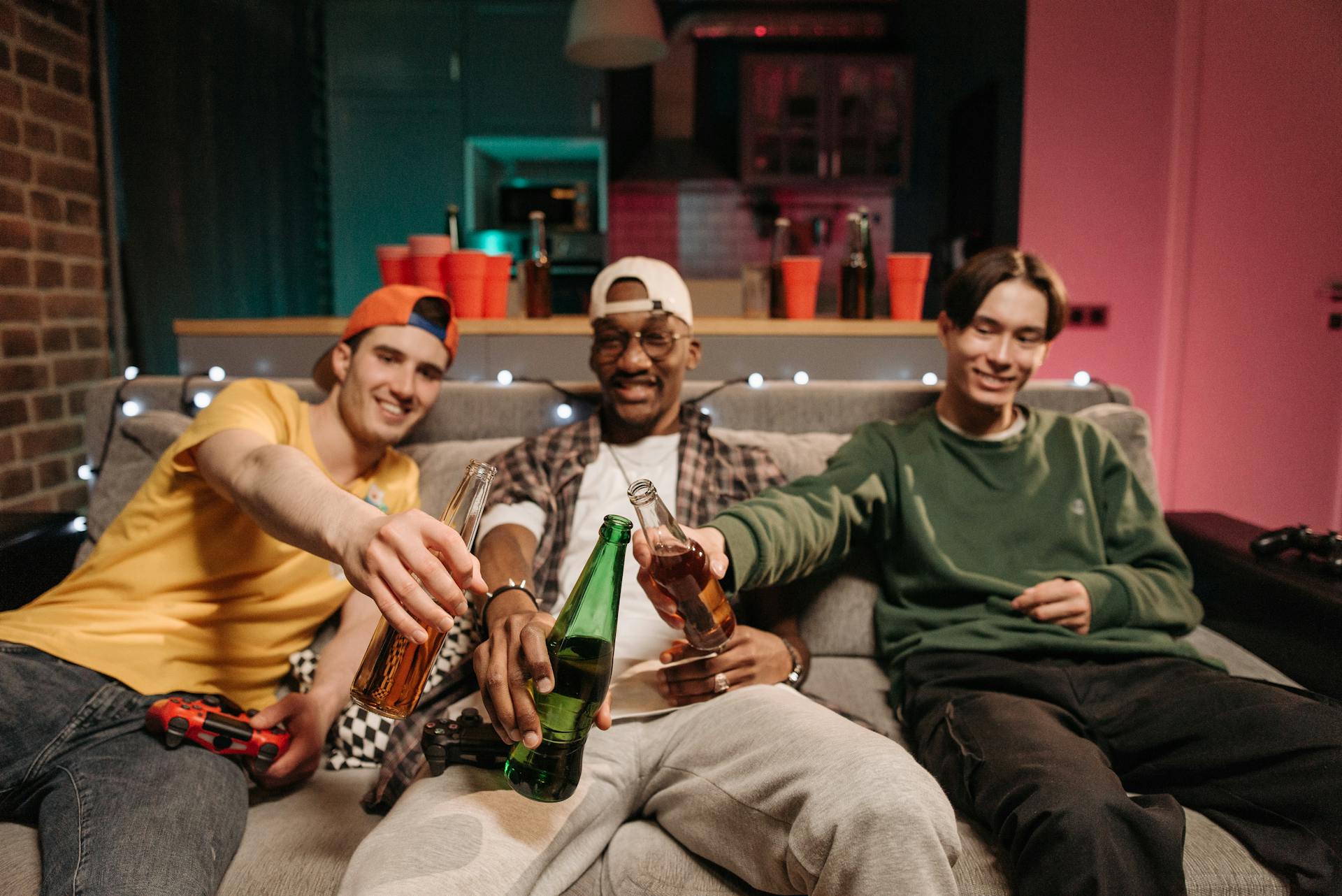 Uomini che brindano con le loro bottiglie di birra durante una serata di gioco a casa | Fonte: Pexels