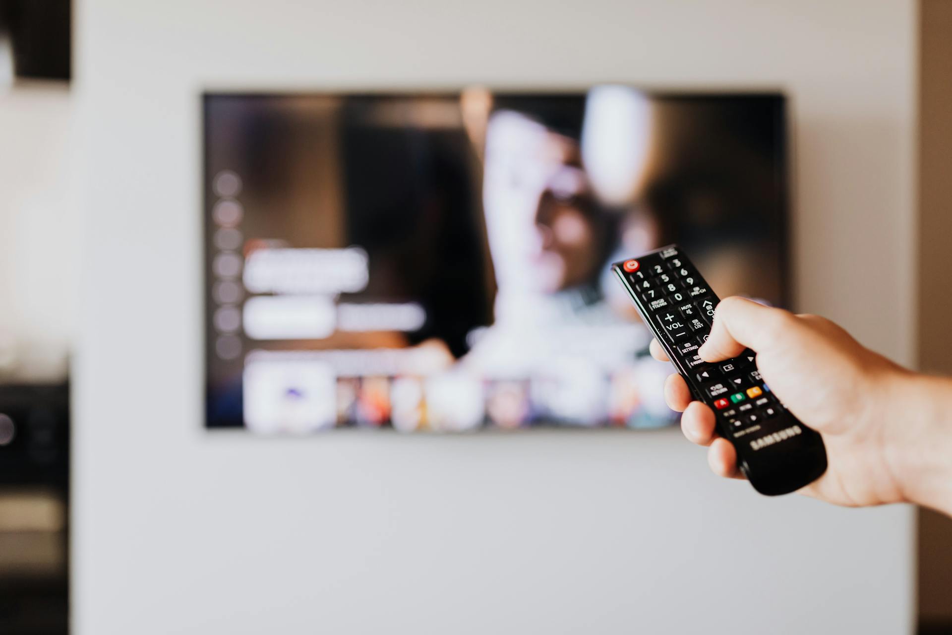 Un hombre sujetando el mando a distancia de un televisor | Fuente: Pexels