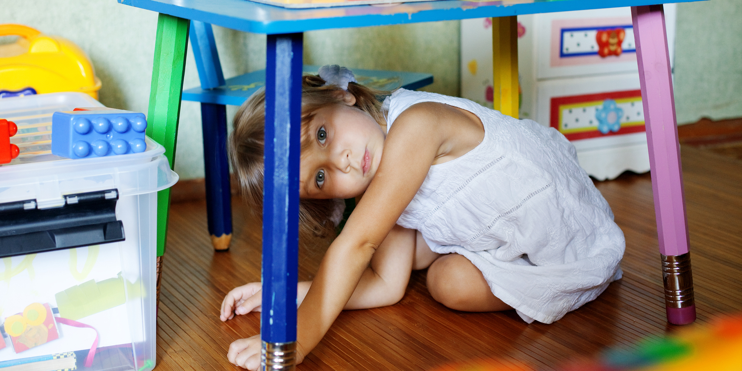 Un niño escondido debajo de una mesa | Fuente: Shutterstock