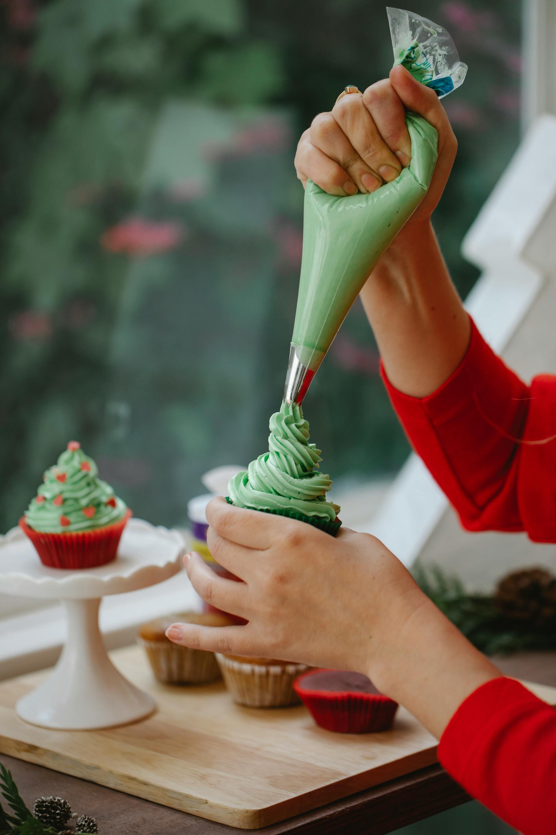 Primer plano de una mujer decorando una magdalena casera con nata | Fuente: Pexels