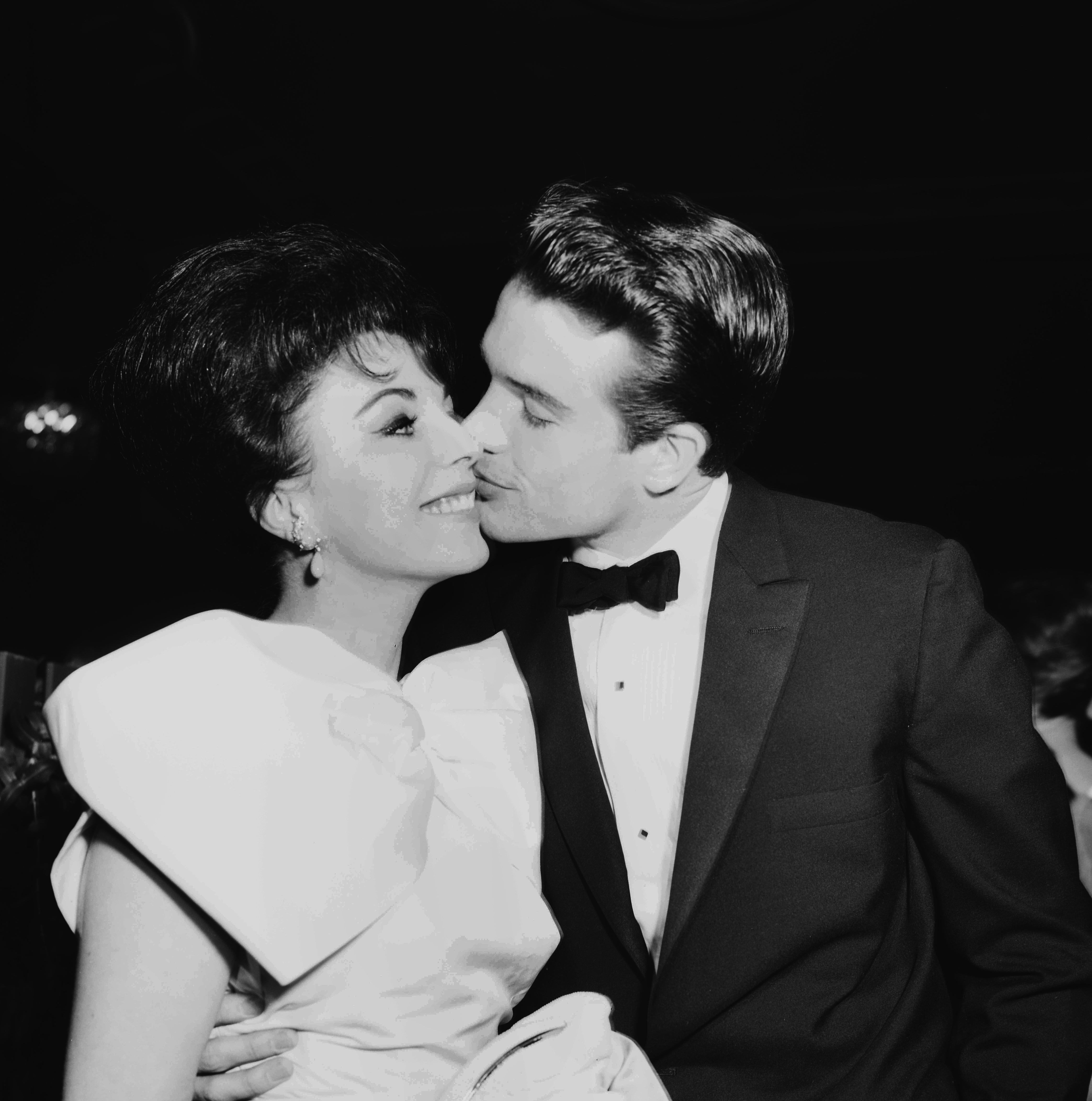 Warren Beatty besa a Joan Collins mientras asisten a una fiesta en Los Ángeles, California, en 1959. | Fuente: Getty Images