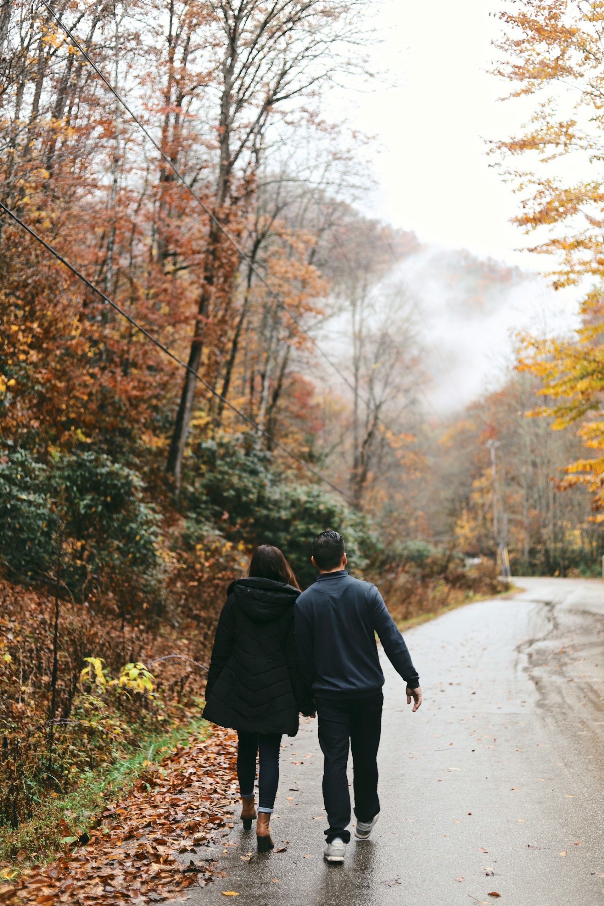 Una pareja tomada de la mano, caminando por la carretera | Fuente: Unsplash