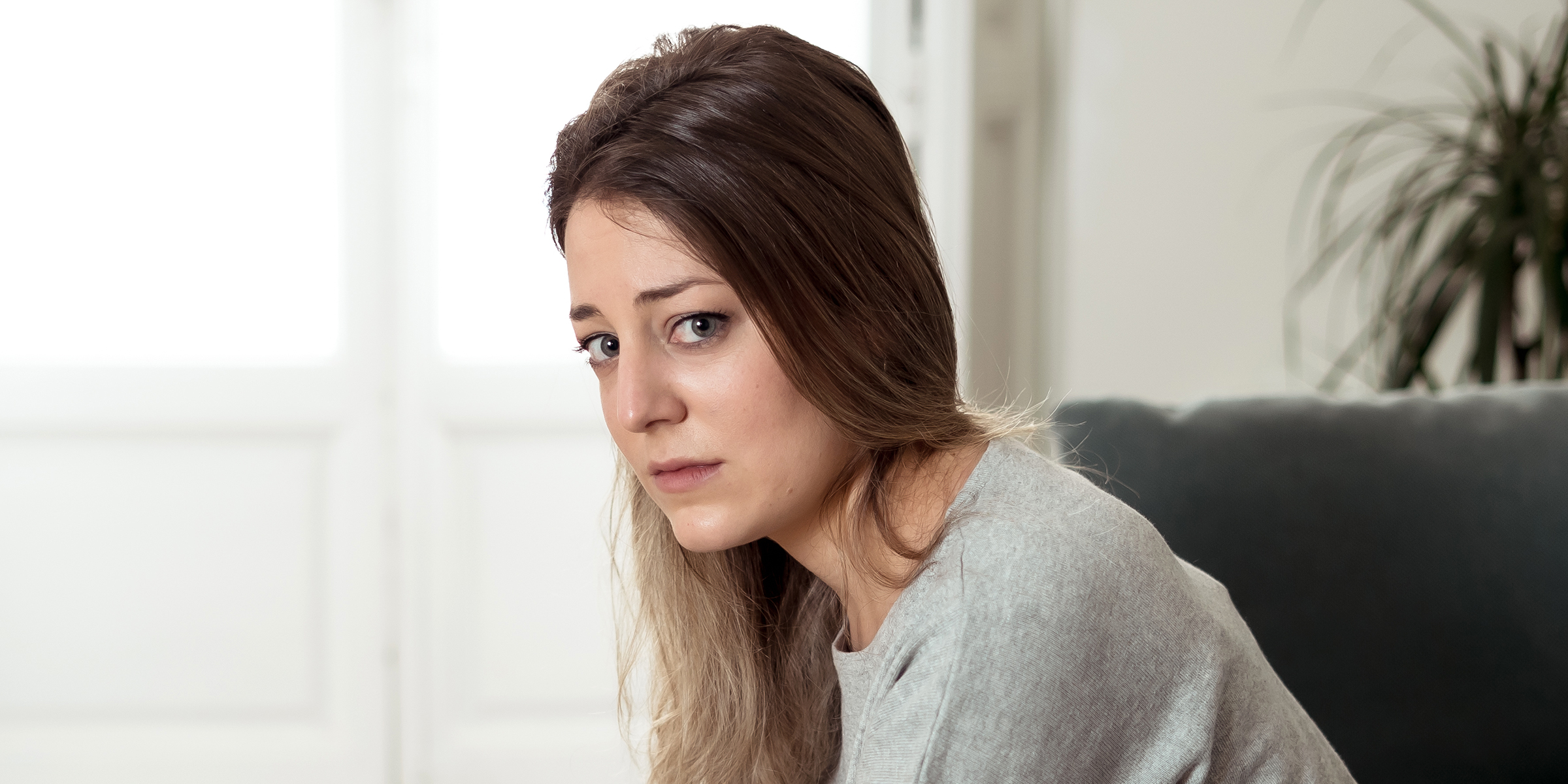 Una mujer de aspecto triste sentada sola en casa | Fuente: Shutterstock