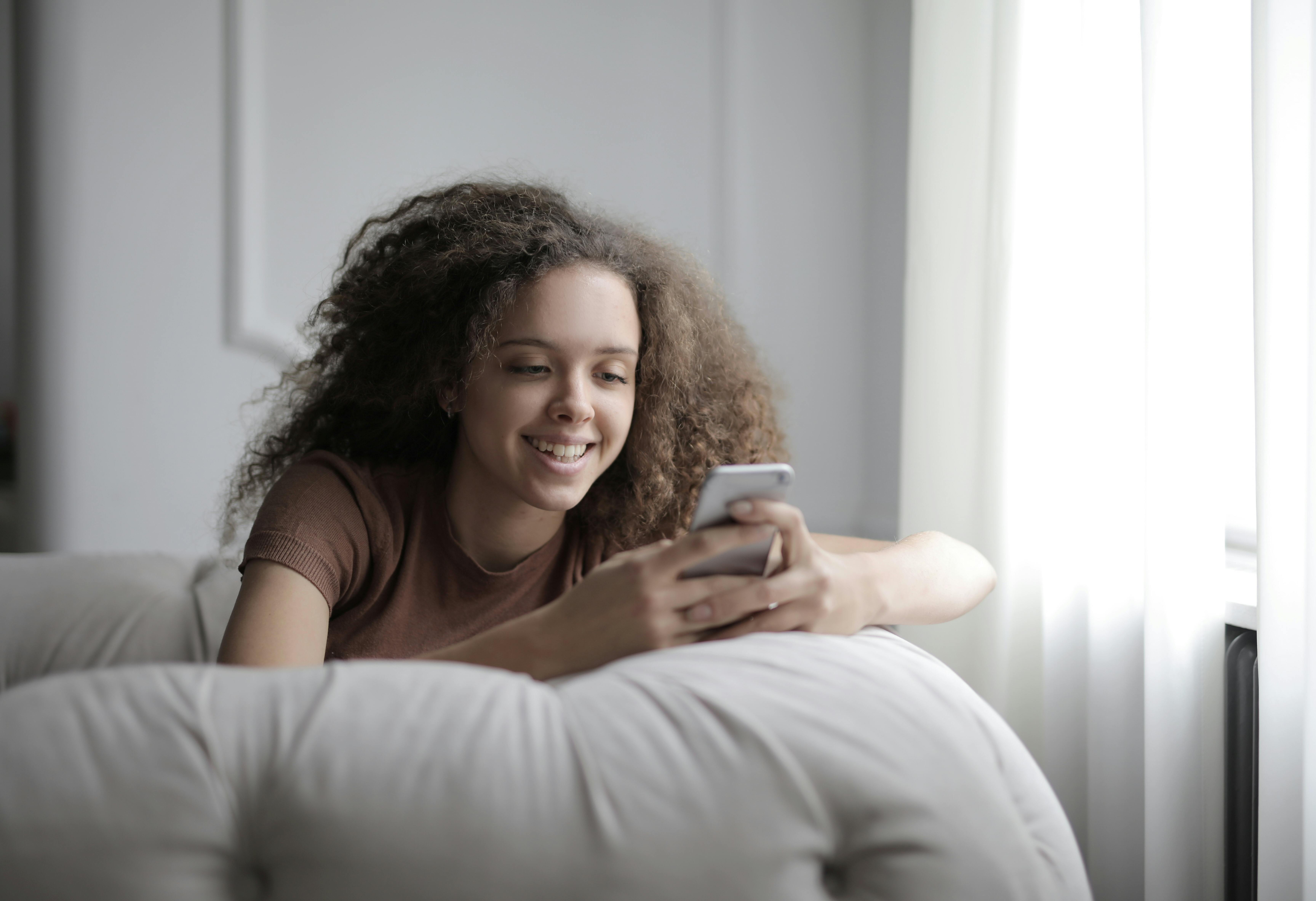 Una chica feliz con su teléfono | Fuente: Pexels