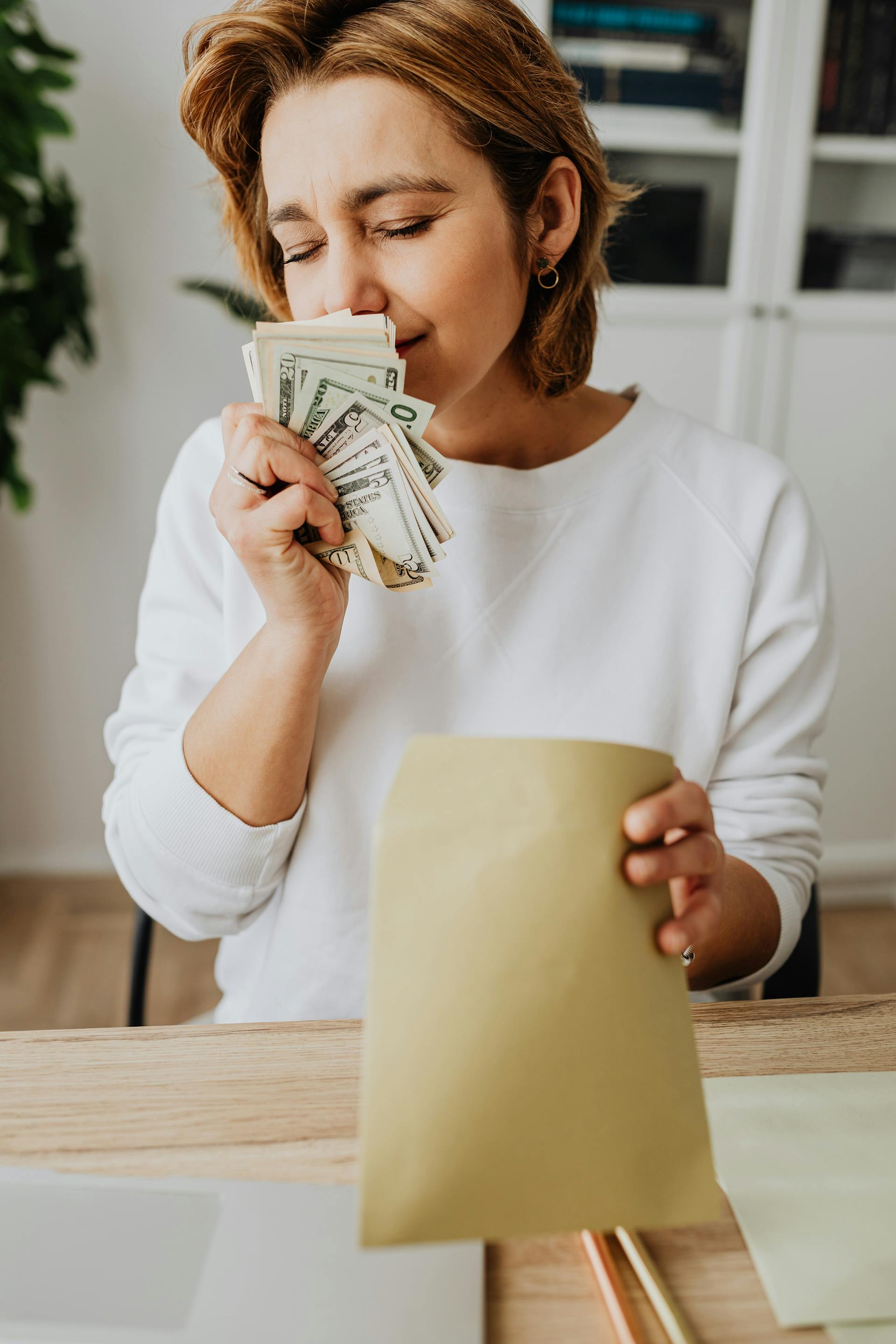 Una mujer oliendo dinero con los ojos cerrados | Fuente: Pexels