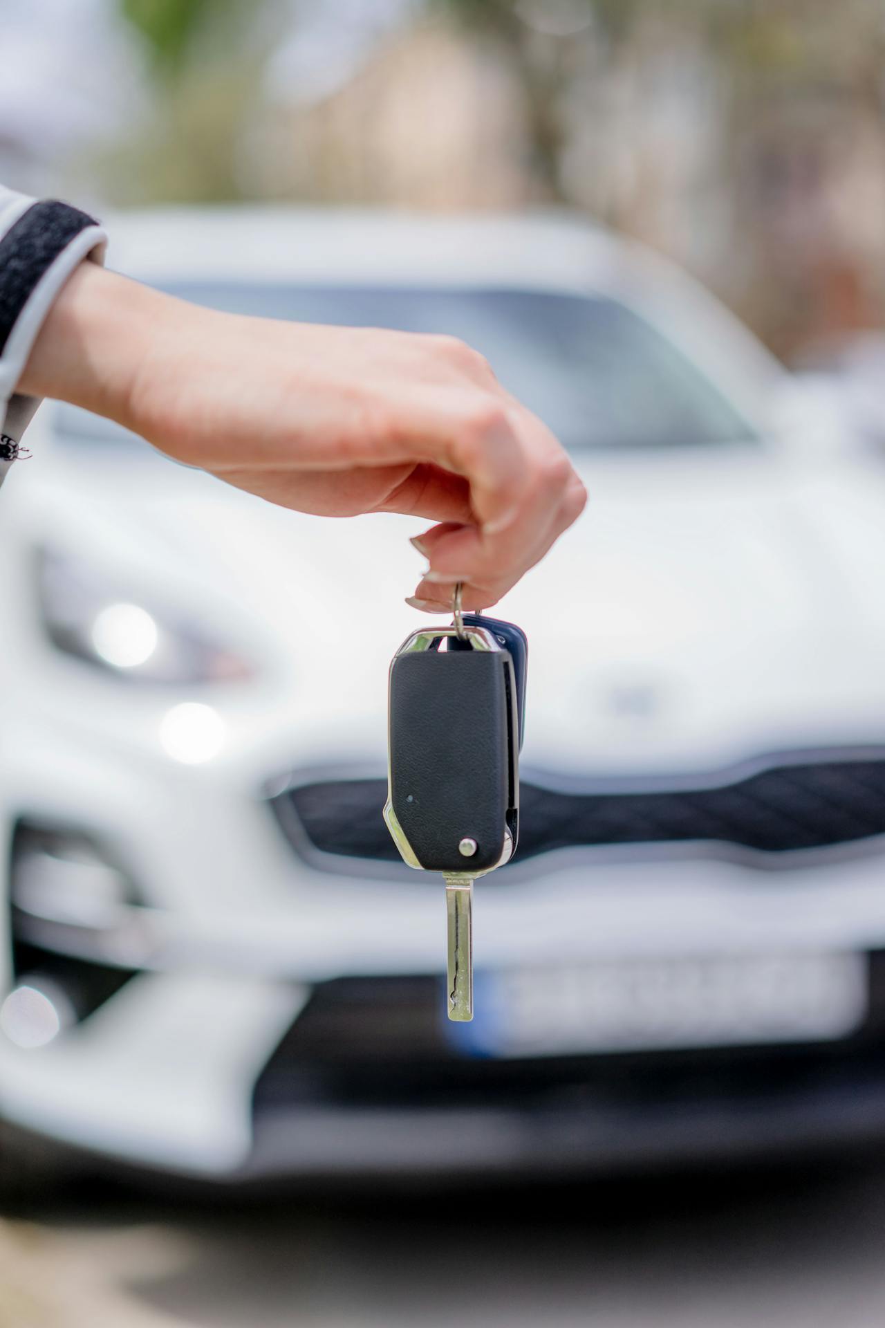 Una mujer con la llave de un automóvil en la mano y delante de su coche | Fuente: Pexels