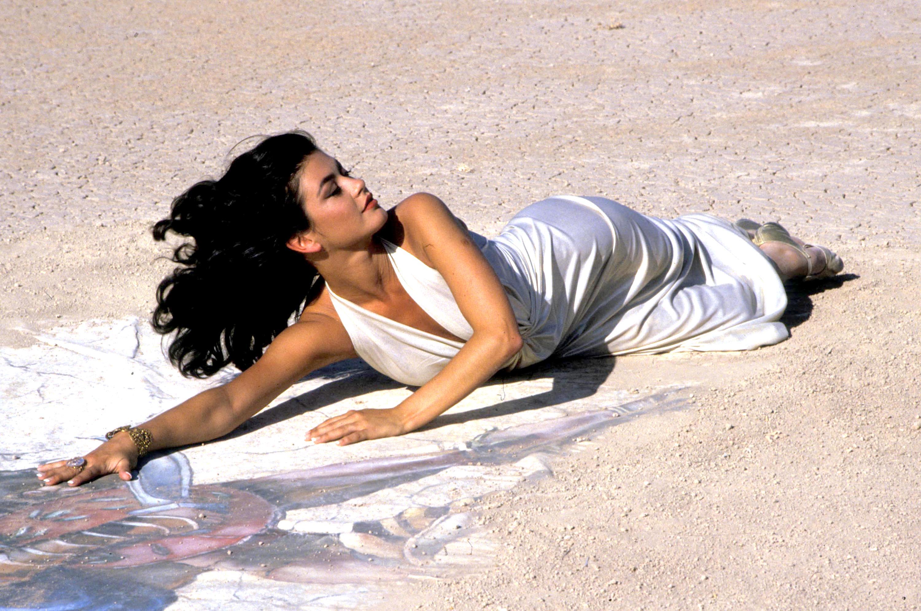 En esta fotografía de los inicios de su carrera, Catherine Zeta-Jones posó con un vestido blanco fluido y su cabello largo y oscuro suelto, años antes de que "The Mask of Zorro" la consolidara como una de las bellezas más célebres de Hollywood. | Fuente: Getty Images