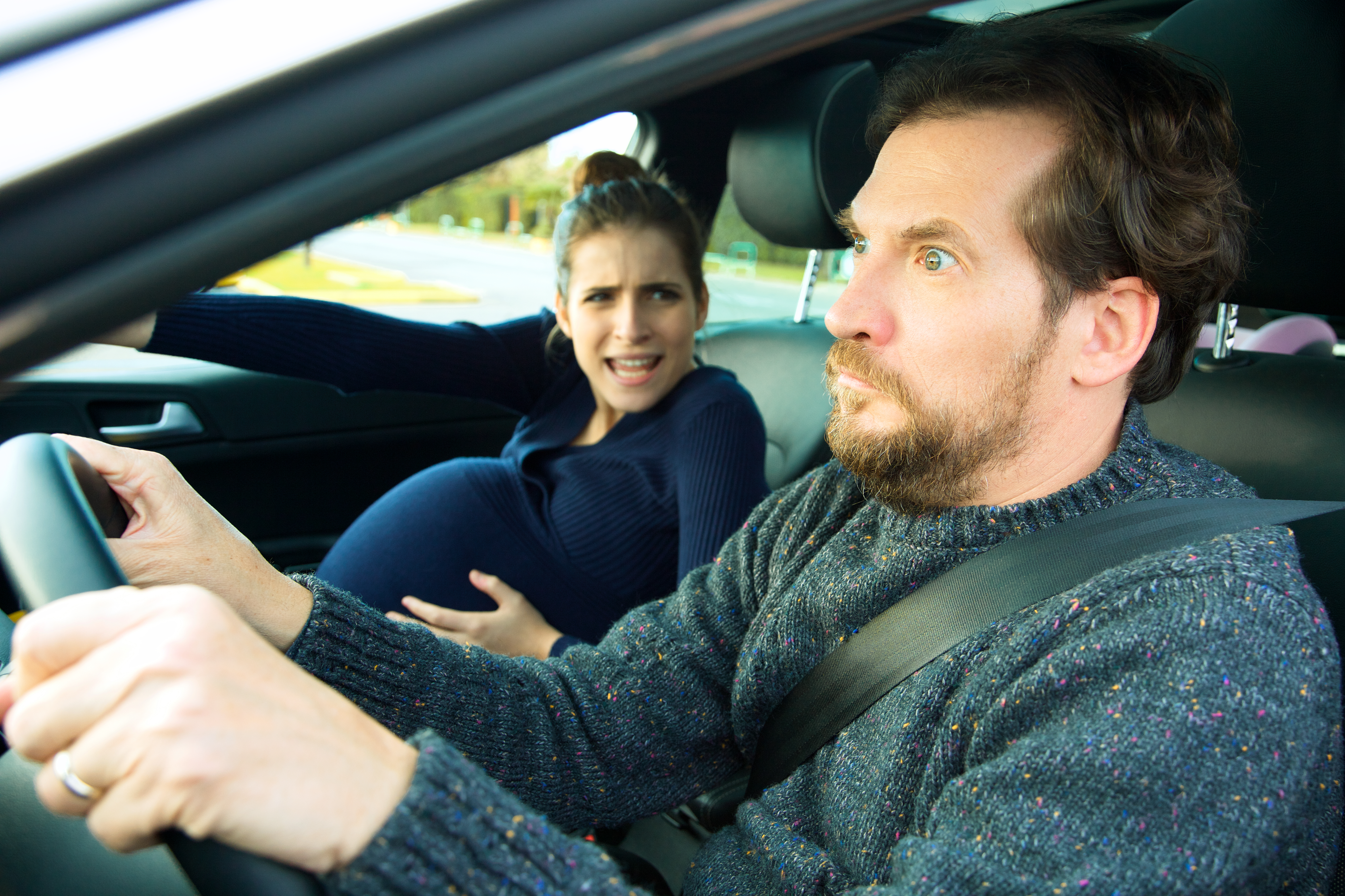 Hombre con cara de terror conduce con una mujer embarazada | Fuente: Shutterstock