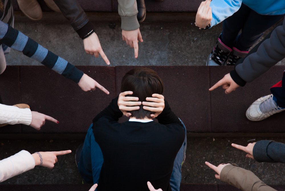 Grupo de estudiantes intimidando a un joven.|Fuente: Shutterstock