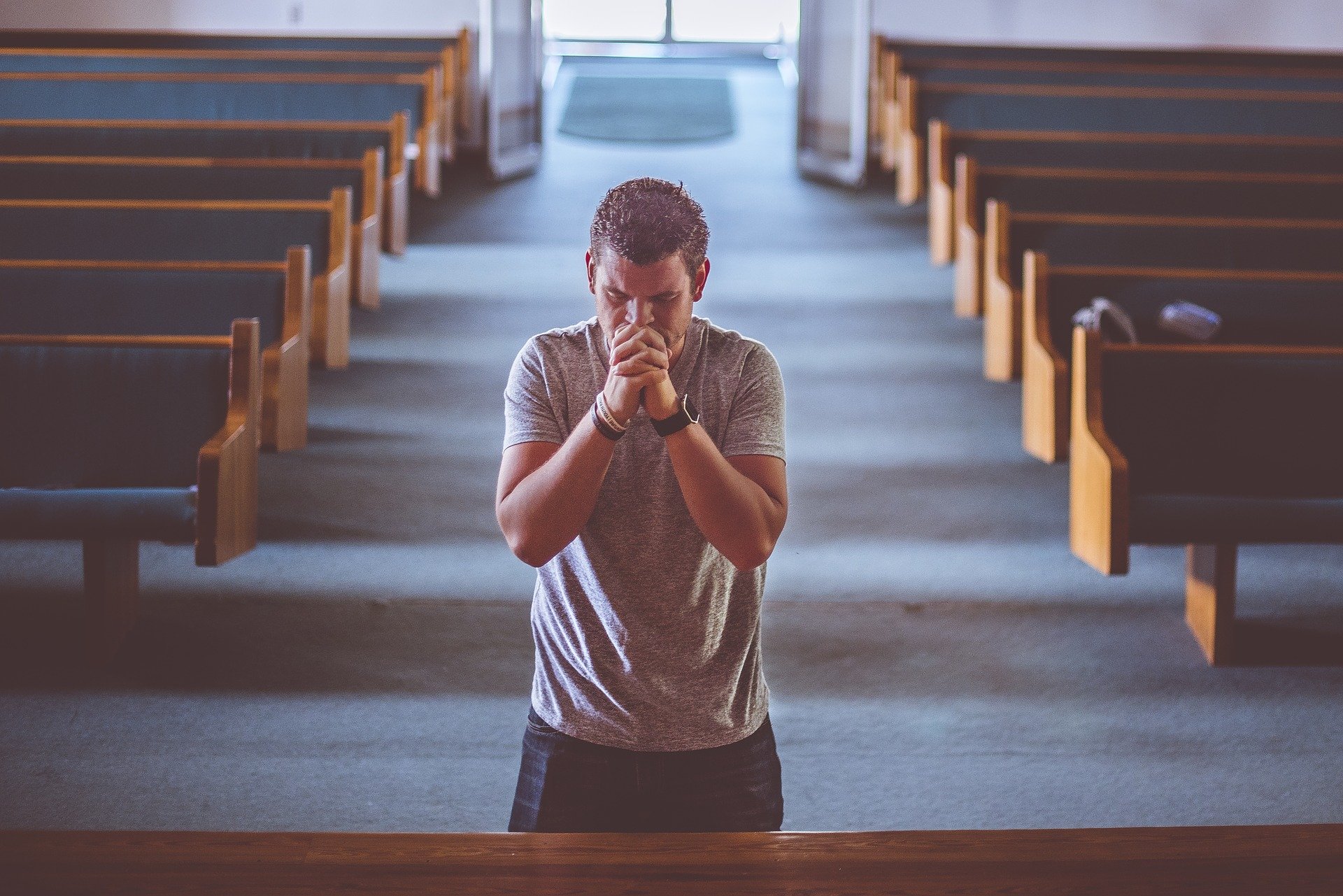 Joven orando en una iglesia. │Foto: Pixabay