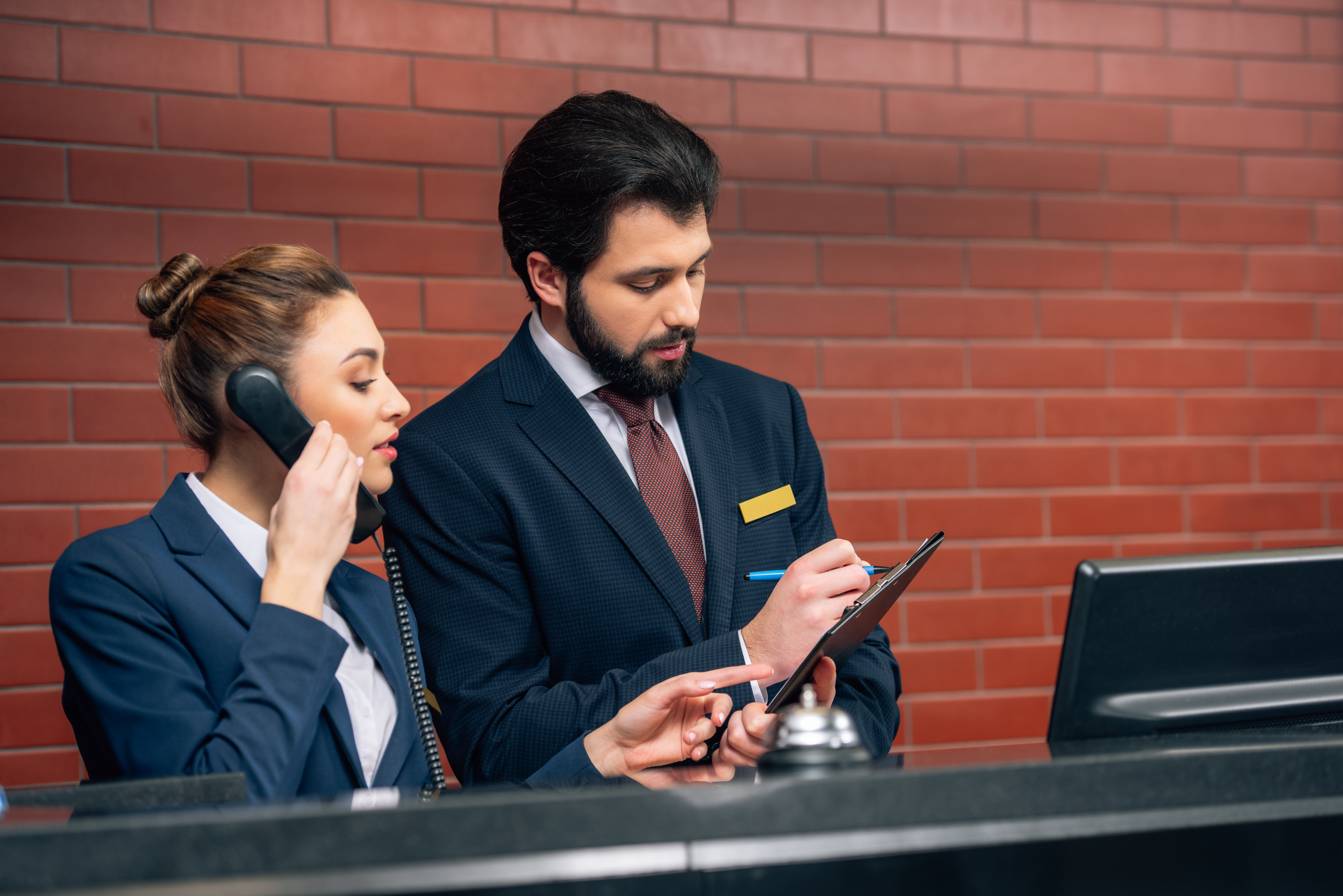 Recepcionistas de hotel concentrados recibiendo la llamada de un cliente en su lugar de trabajo. | Fuente: Shutterstock