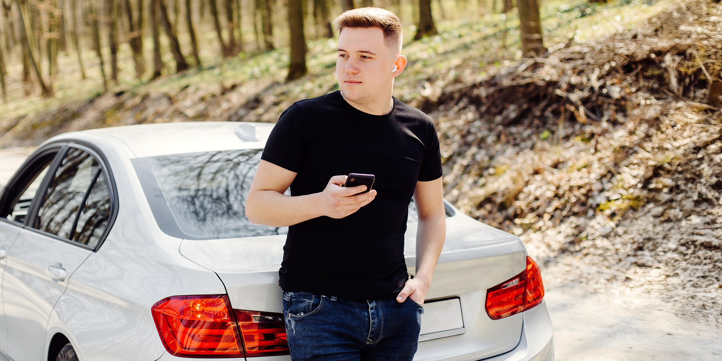 Un hombre de pie junto a un automóvil y sosteniendo un teléfono | Fuente: Shutterstock