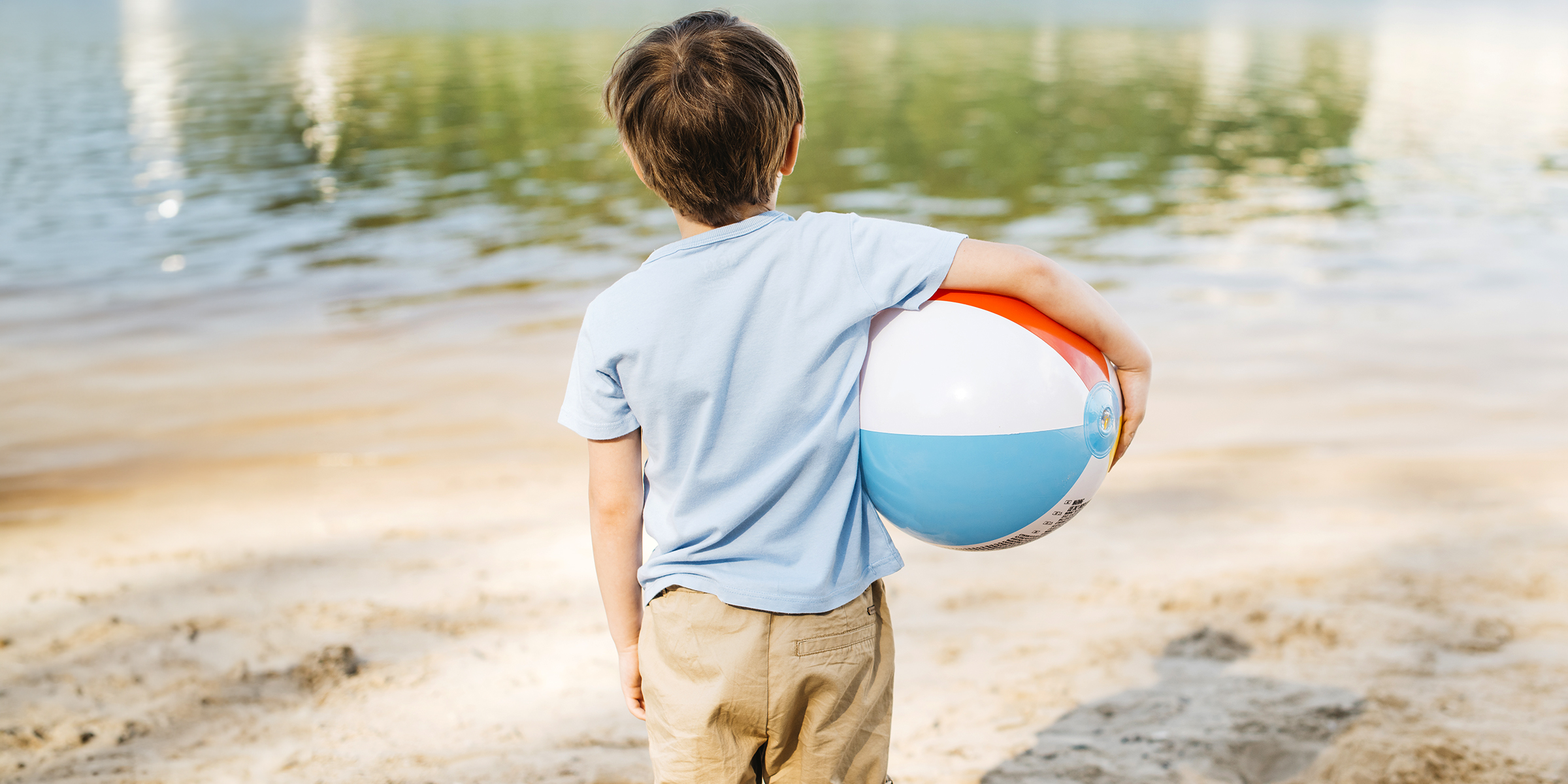 Un niño sujetando una pelota en la playa | Fuente: Freepik