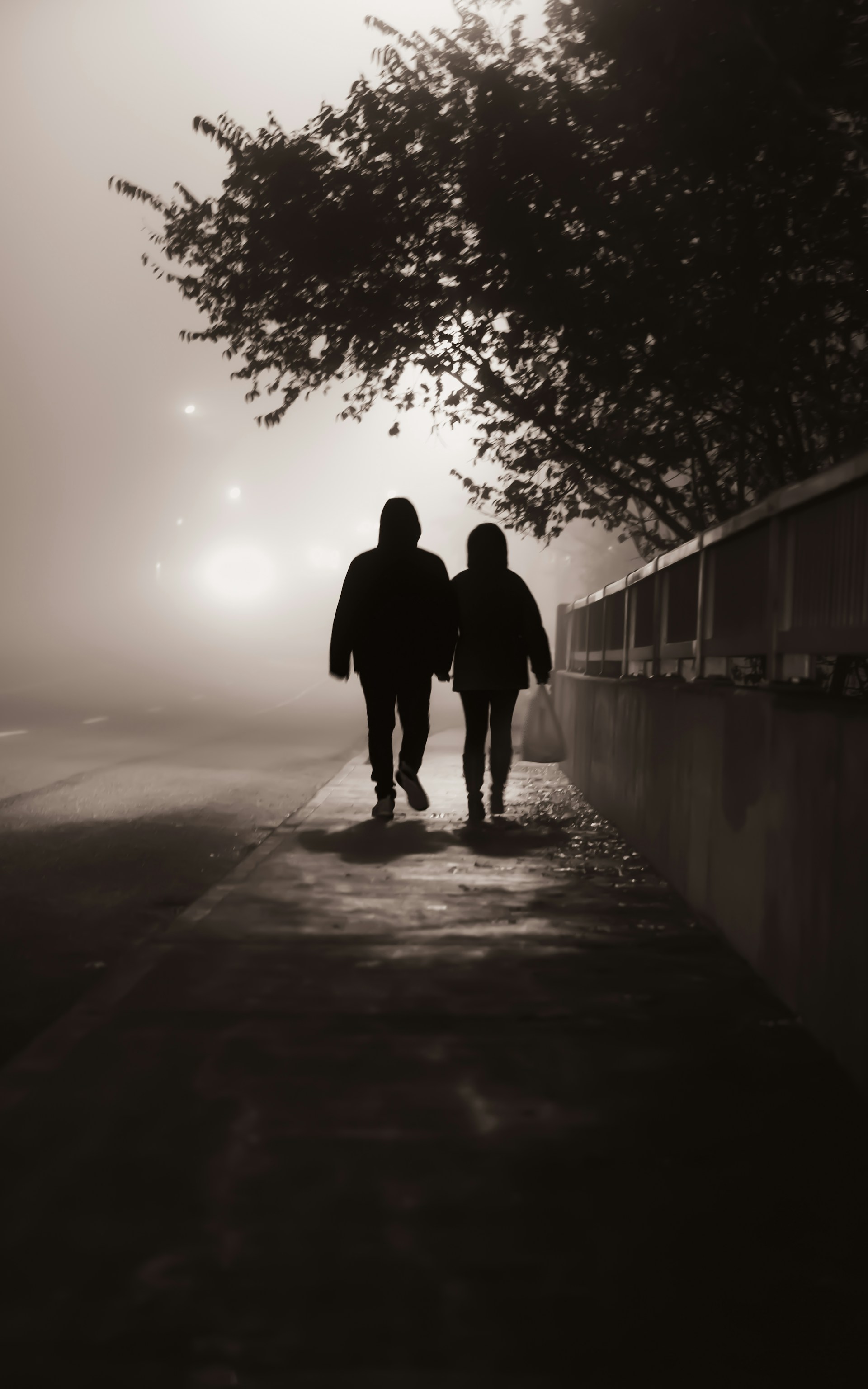 Una pareja paseando por la acera en una tarde brumosa | Fuente: Unsplash