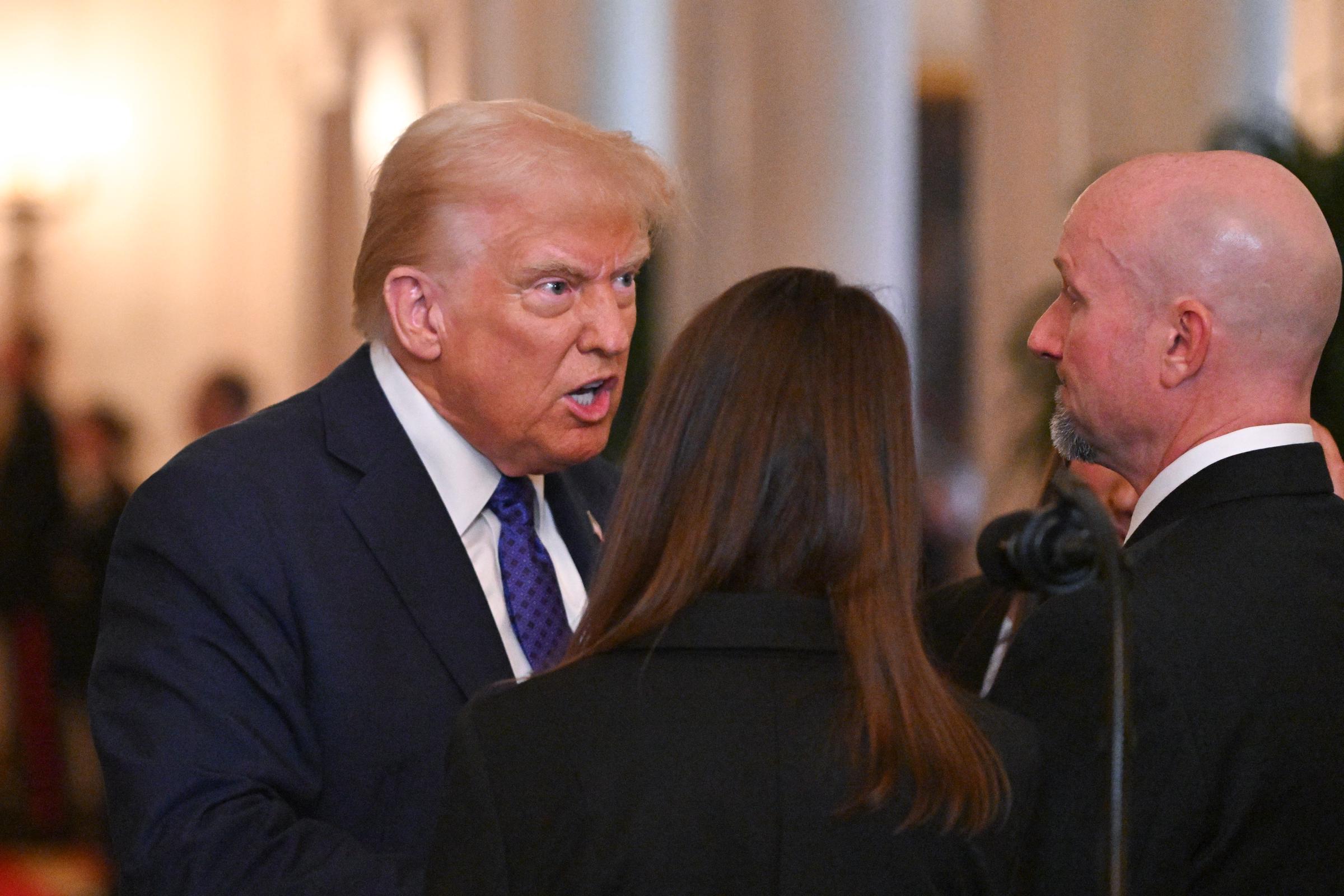 El presidente de EEUU, Donald Trump, habla con Allyson Phillips, madre de Laken Riley, y John Phillips, padrastro de Laken Riley, antes de firmar la Ley Laken Riley en la Sala Este de la Casa Blanca en Washington, D.C., 29 de enero de 2025. | Fuente: Getty Images