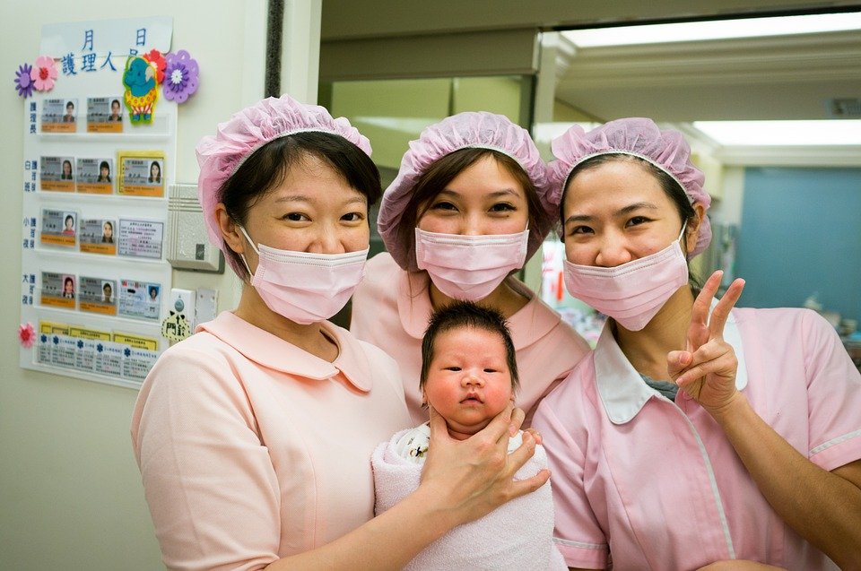 Enfermeras posando con bebé recién nacido en brazos. | Imagen: Flickr