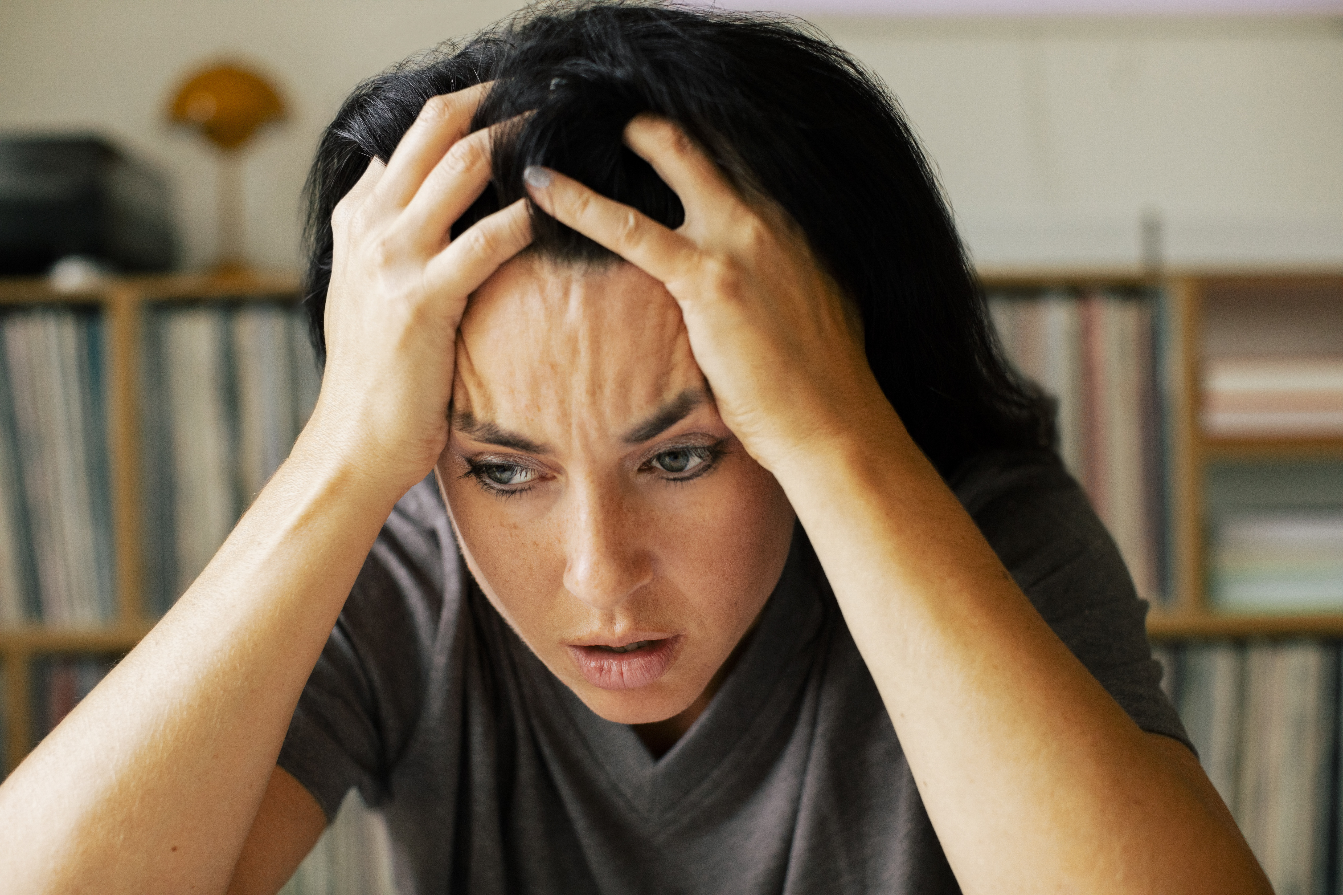 Mujer estresada con la cabeza entre las manos en casa | Fuente: Getty Images