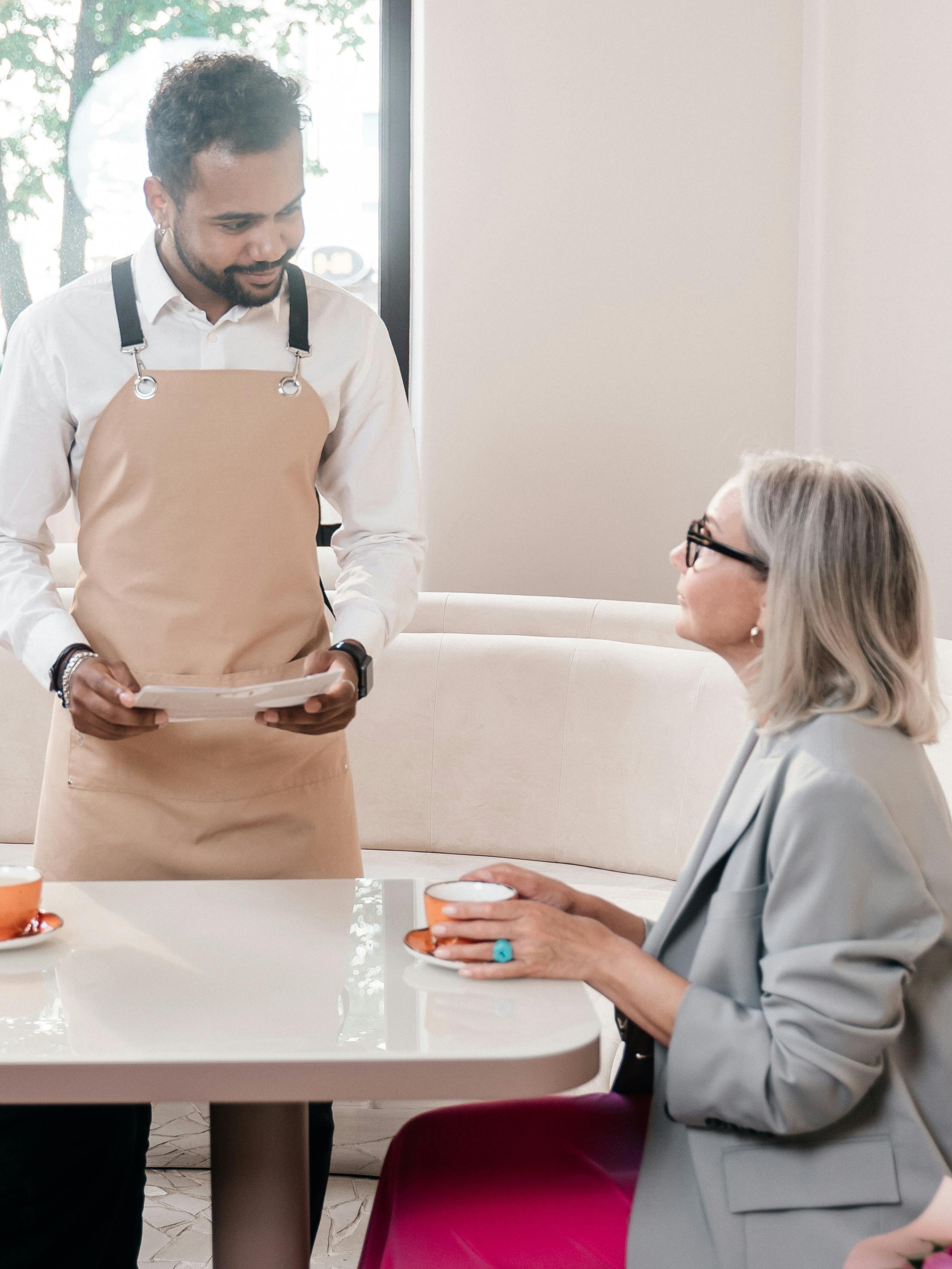 Un camarero discute algo con un cliente de un restaurante | Fuente: Pexels