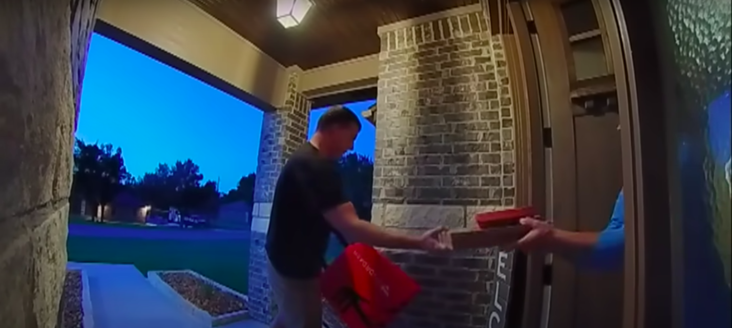 Una captura de pantalla del repartidor de DoorDash entregando a Lacey Purciful su pizza, publicada el 5 de julio de 2023. | Foto: YouTube.com/Inside Edition