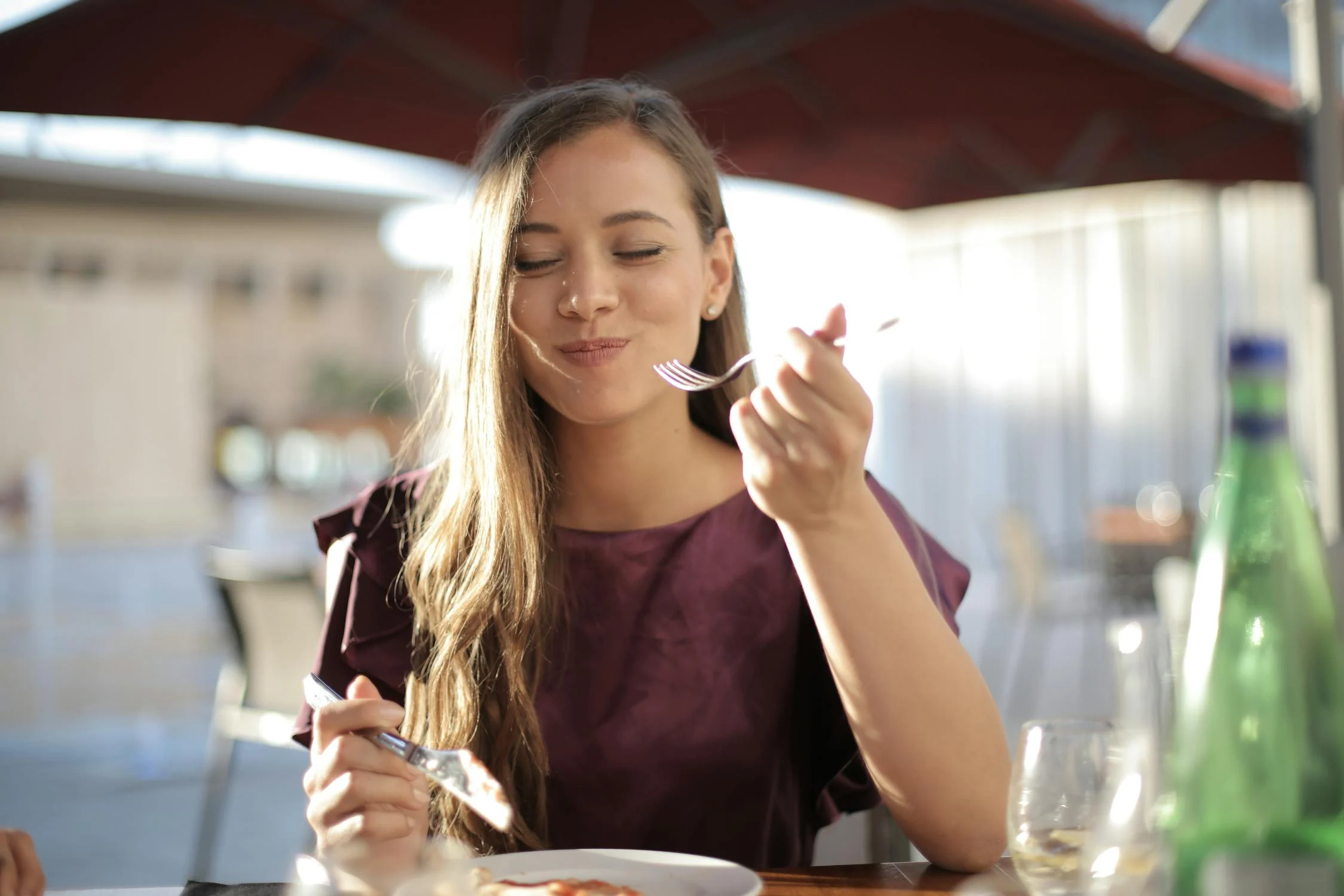 Una mujer sonriente comiendo en una cafetería | Fuente: Pexels