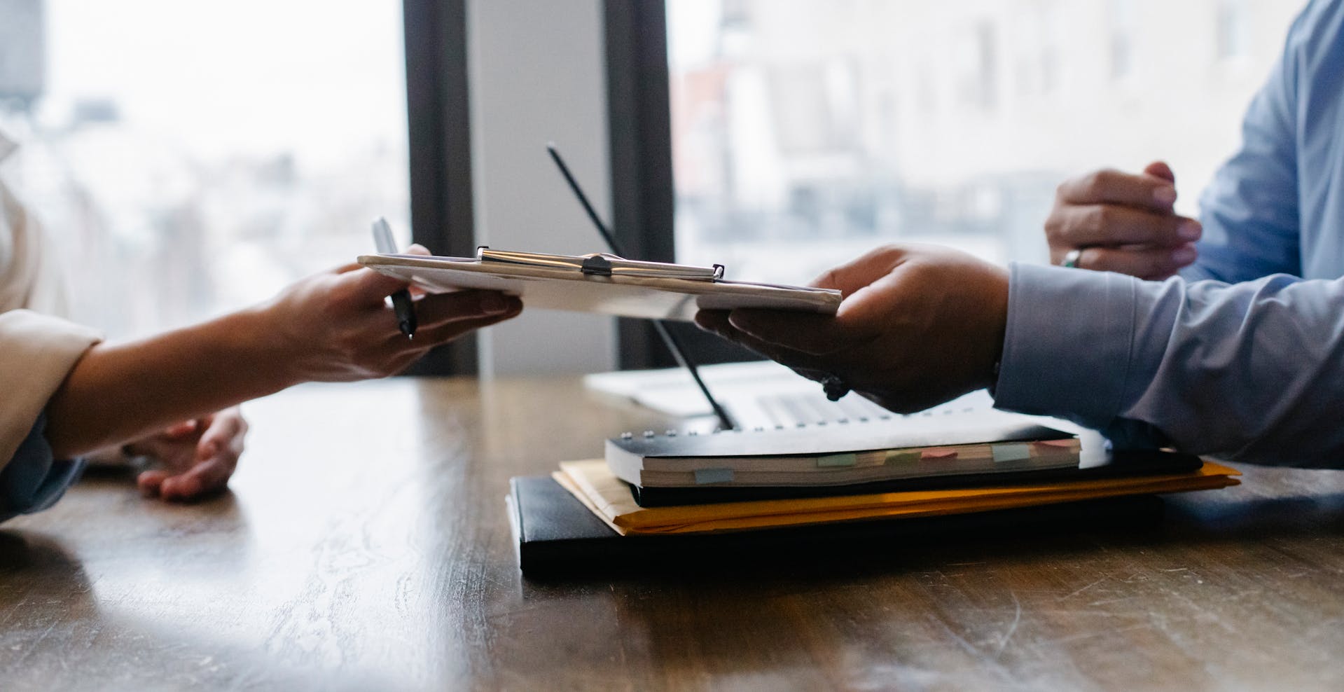 Una mujer pasando su currículum a un empleador | Fuente: Pexels