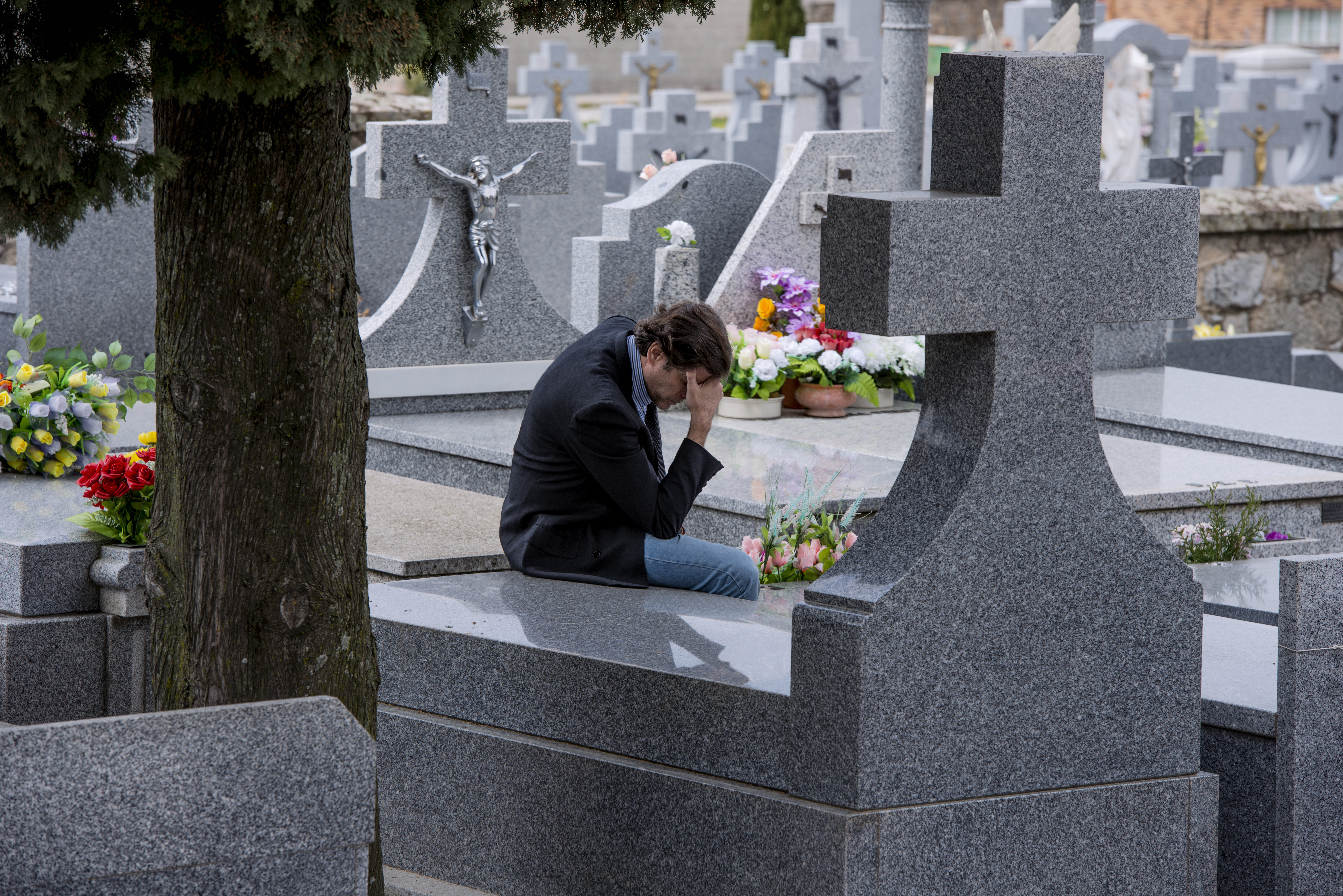 Un hombre sentado frente a una tumba. | Foto: Shutterstock