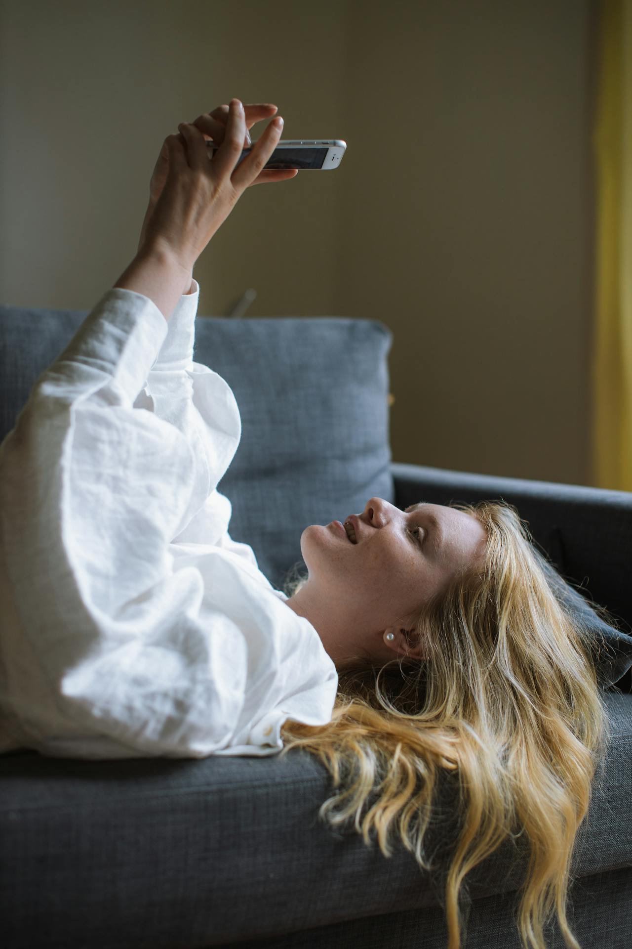 Una mujer tumbada en el sofá y utilizando su teléfono | Fuente: Pexels